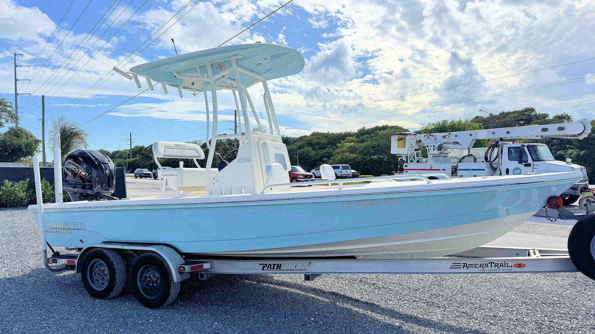 White center-console fishing boat on a trailer in a sunny parking lot