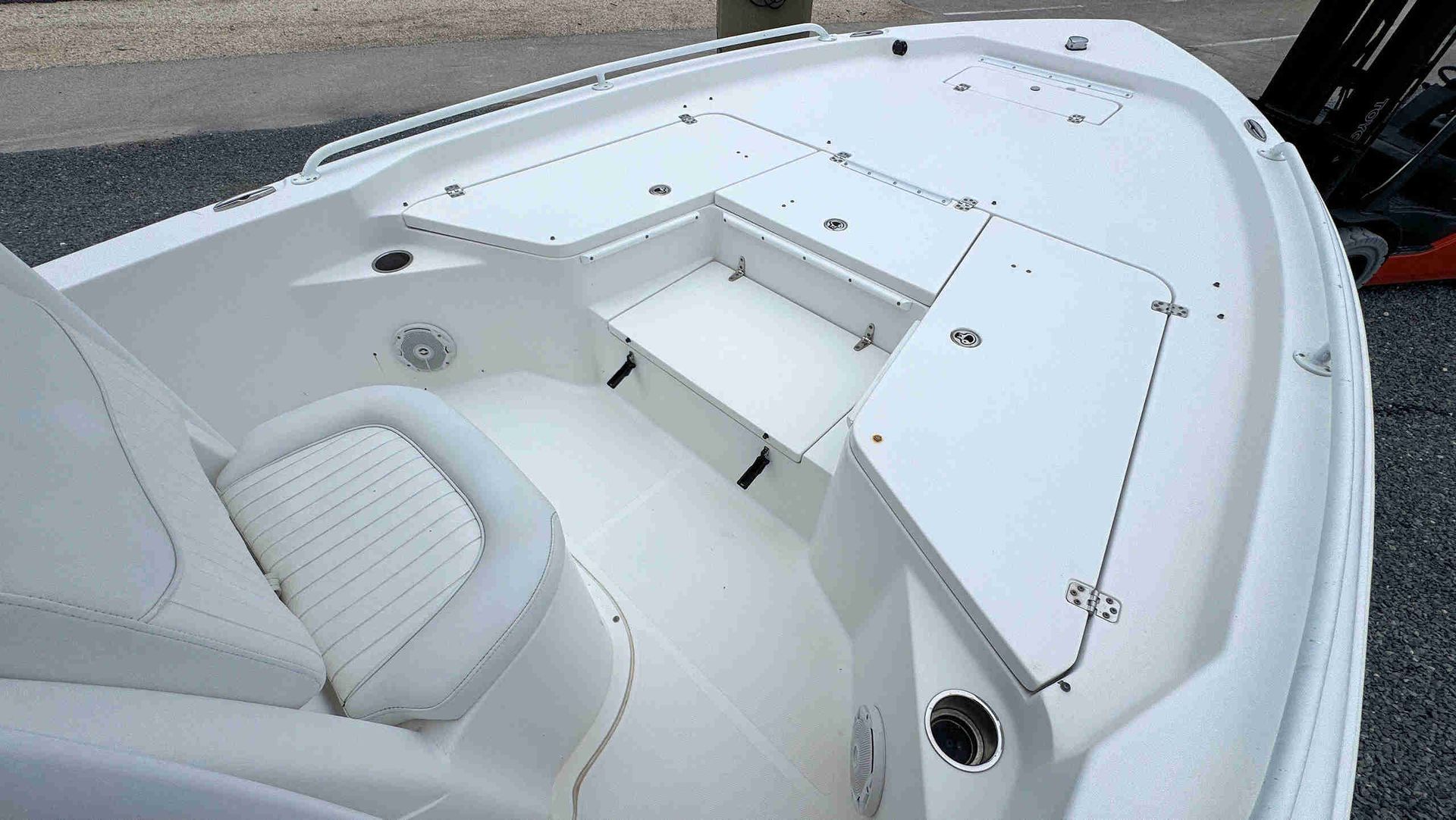 White boat cockpit with cushioned seating and a center storage compartment on a dockside marina.