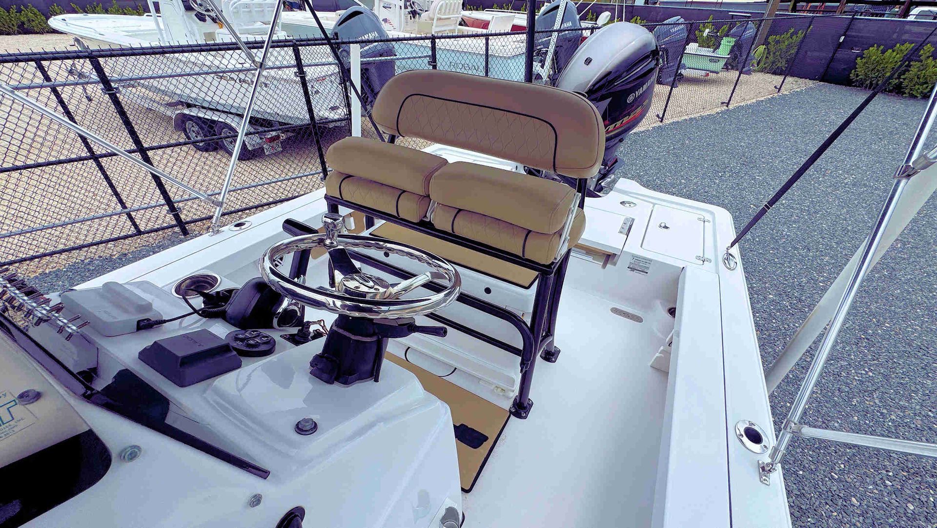 Boat cockpit with tan helm seats, steering wheel, and white deck in a marina setting