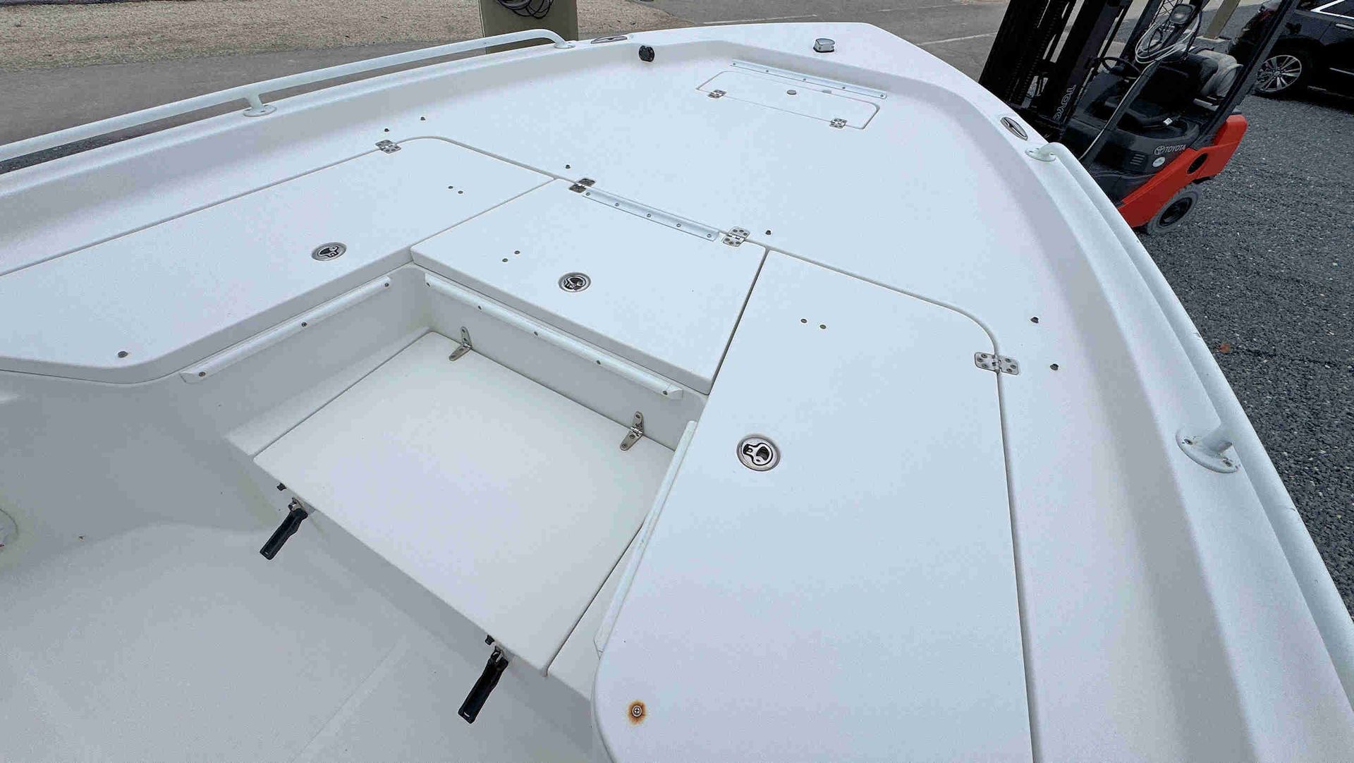 White boat deck with built-in seating and storage hatch near the bow