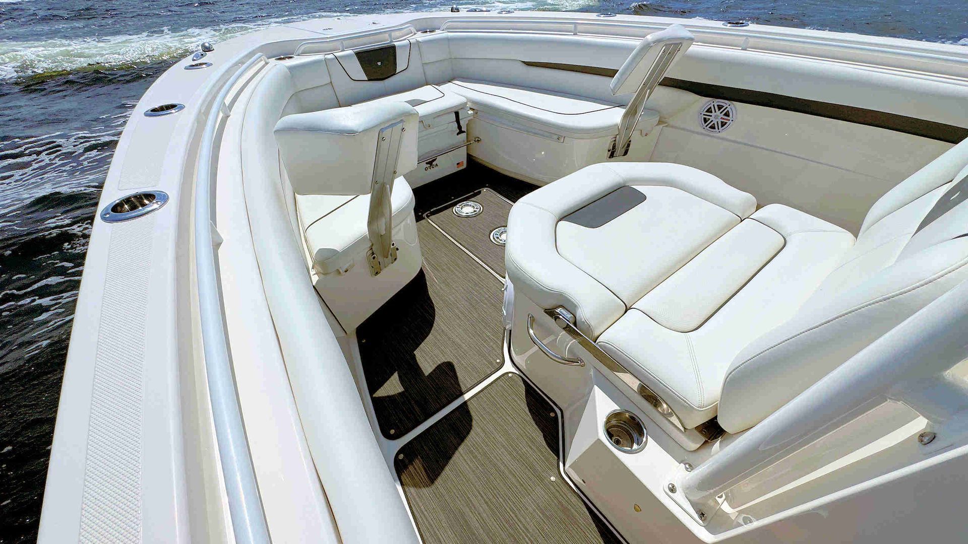 White cushioned seating in the boat bow with helm, under bright sunlight