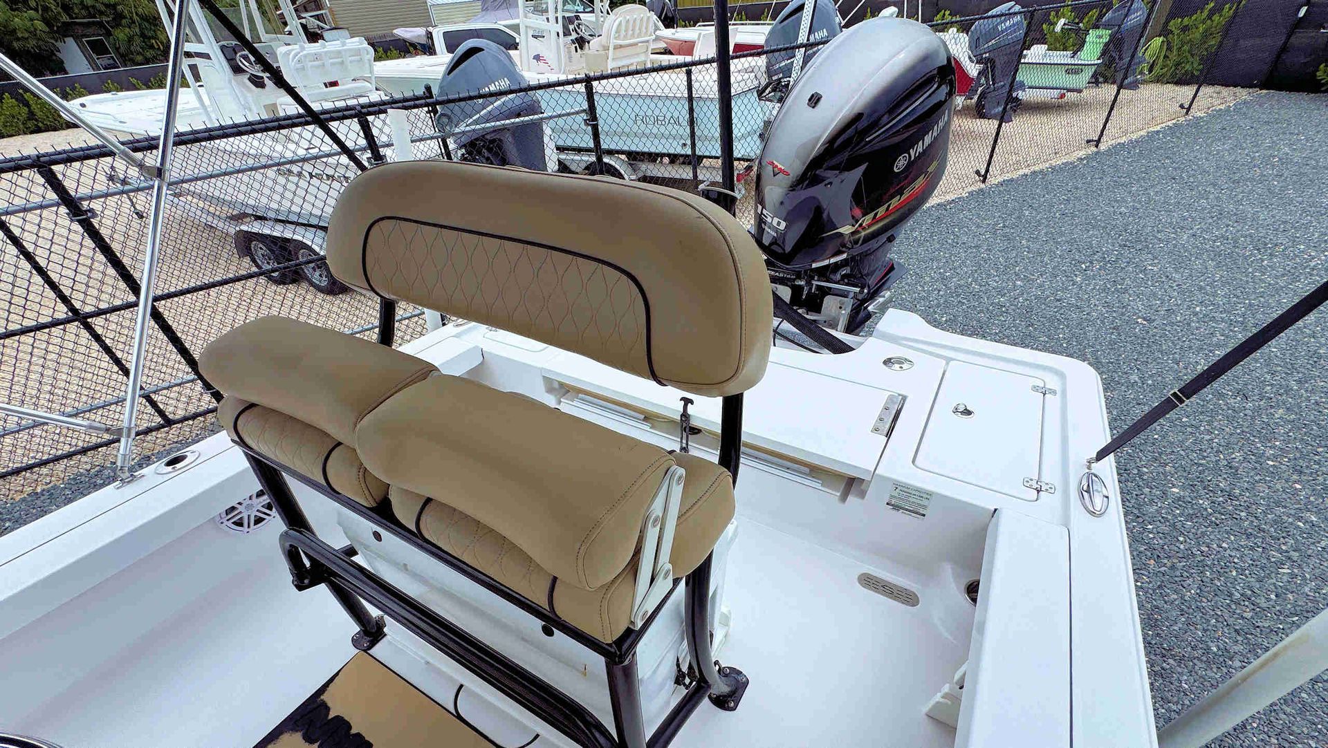 Tan captain's chairs on a small boat deck beside a metal frame and outboard motor, dockside.