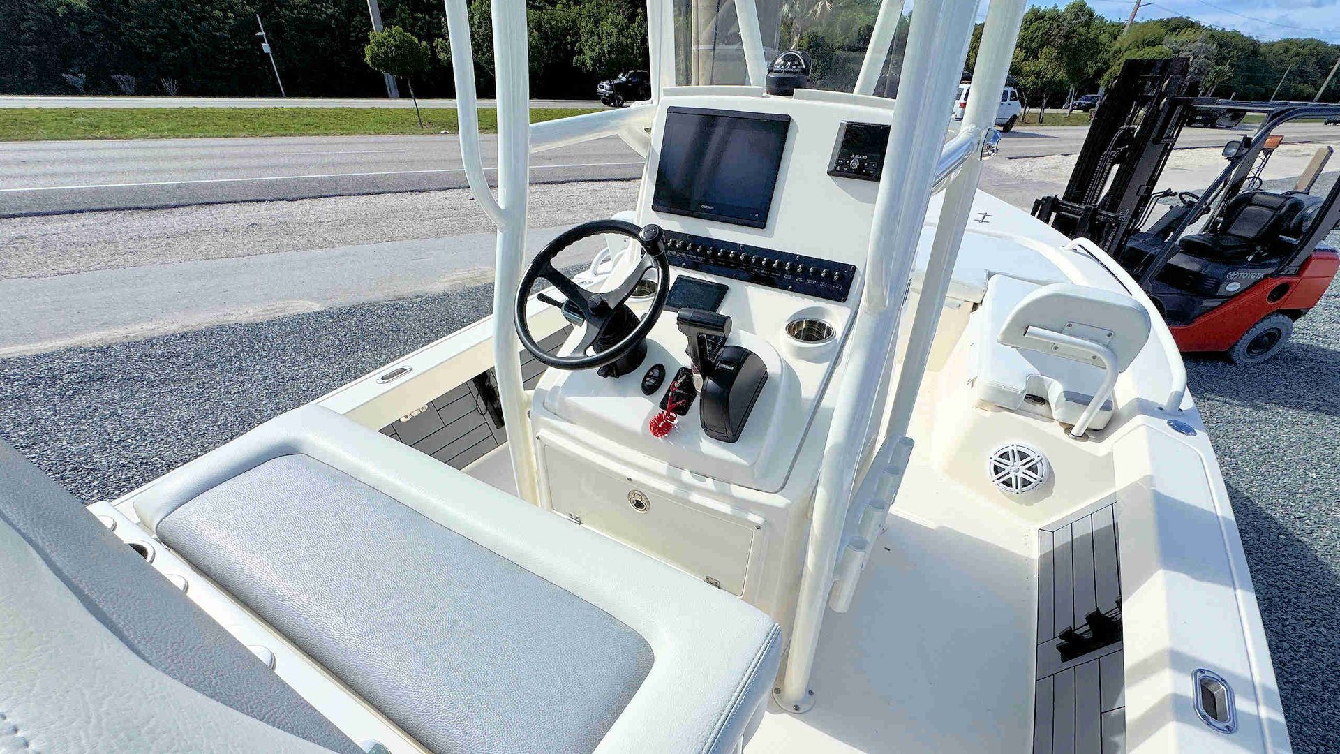 Boat cockpit with gray seating, steering wheel, and dashboard, viewed from the deck side