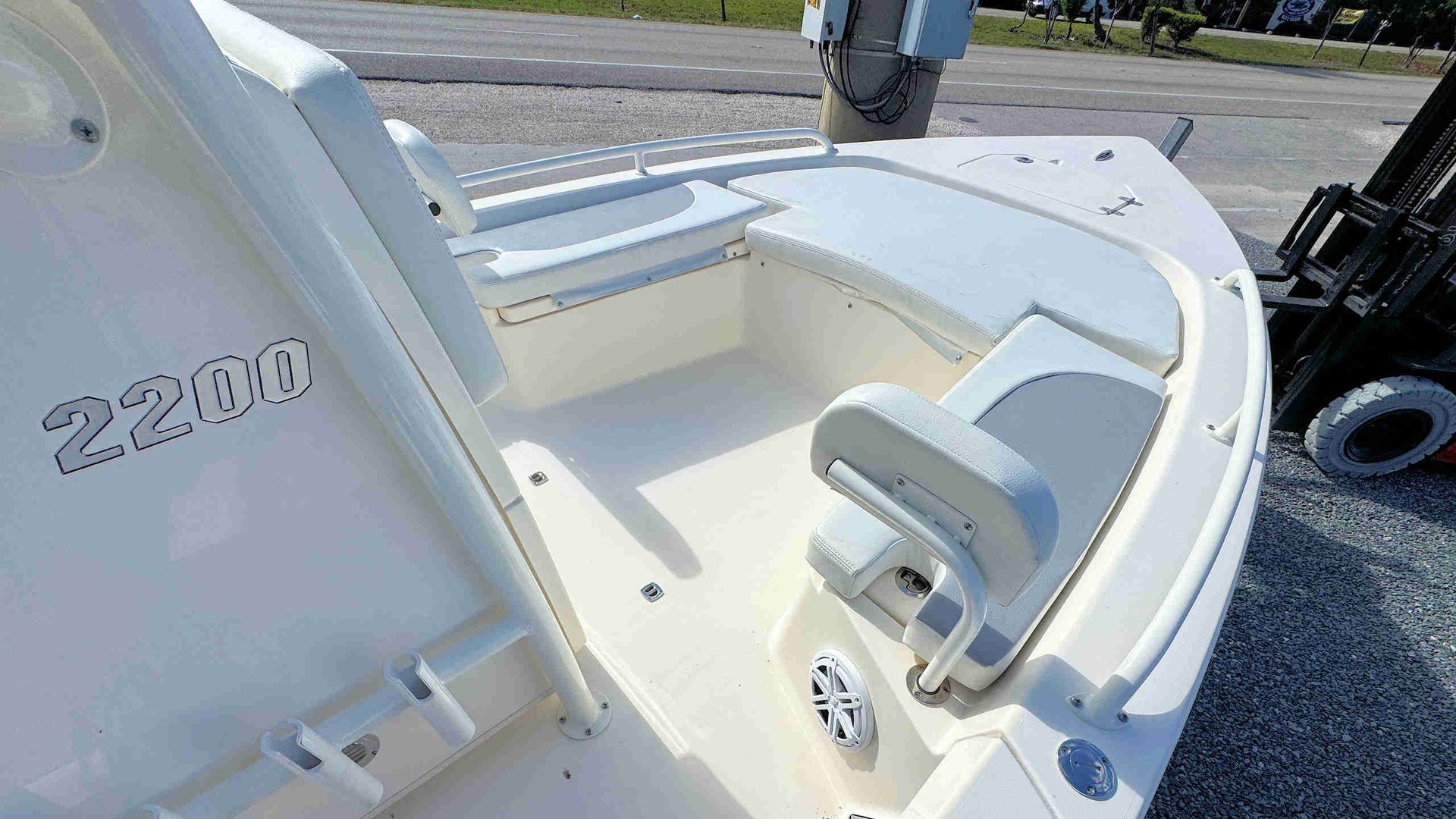 White boat deck with built-in seat and metal railings on a gravel lot, “2200” visible on the side