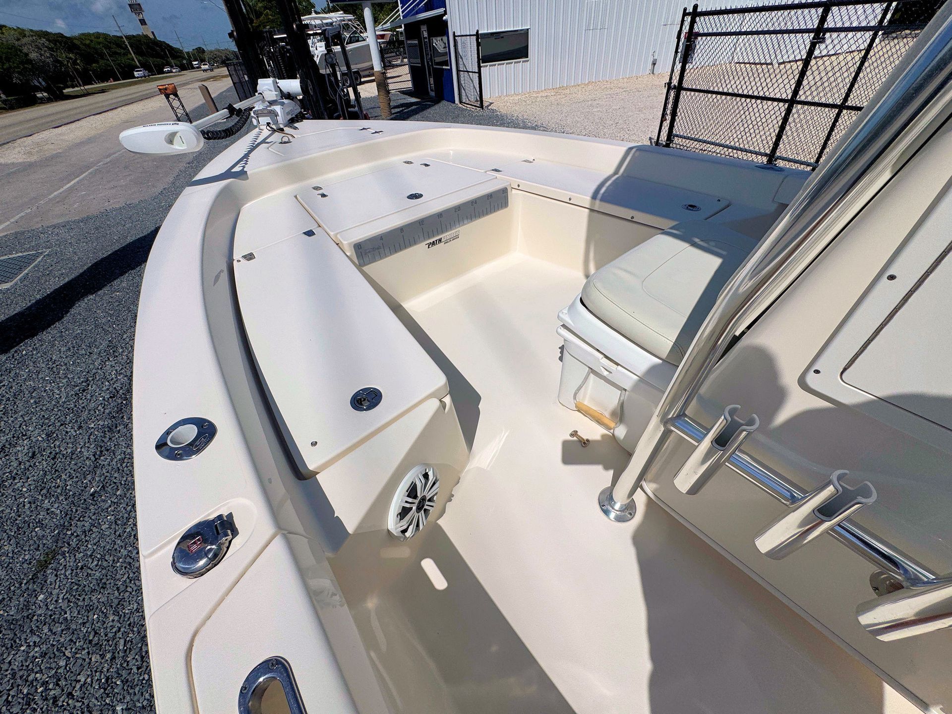 Cream-colored boat deck with a built-in bench seat, railings, and cup holders docked beside a waterfront.