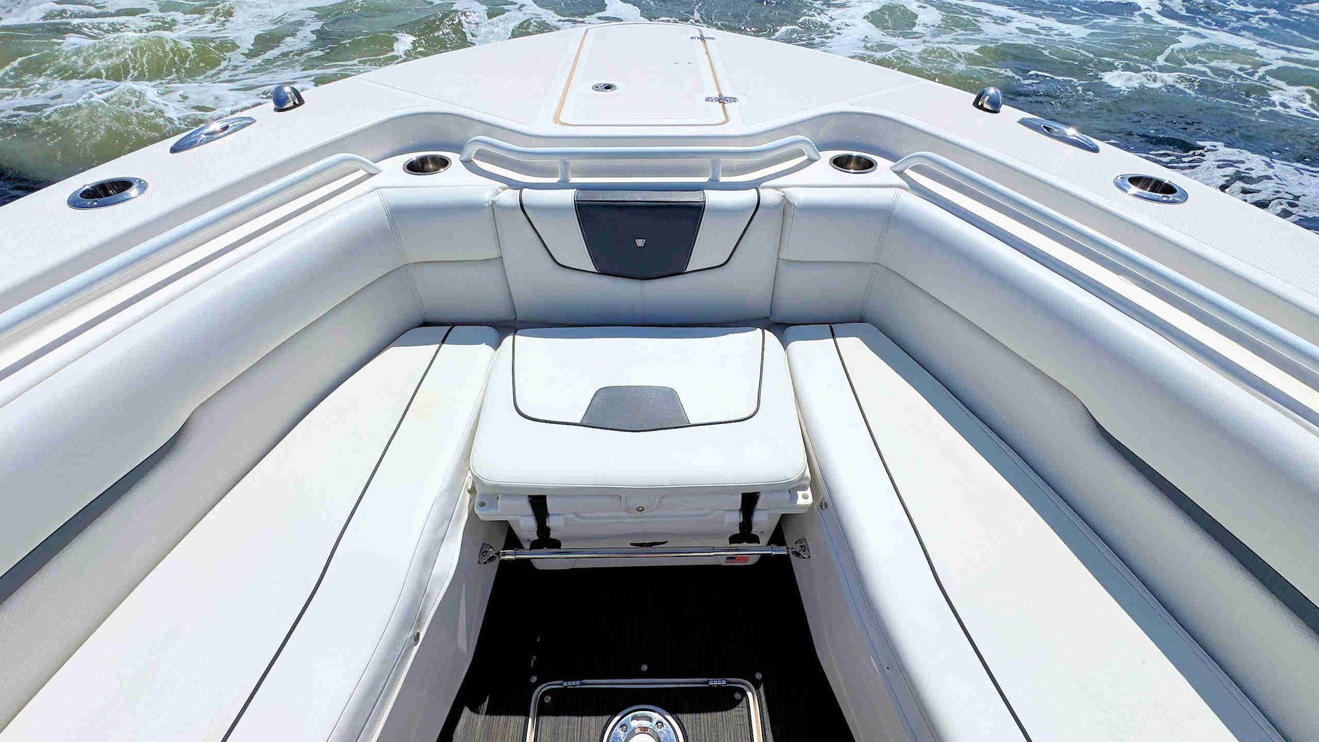 White boat cockpit seating facing the water, with a small center bench and open deck view.
