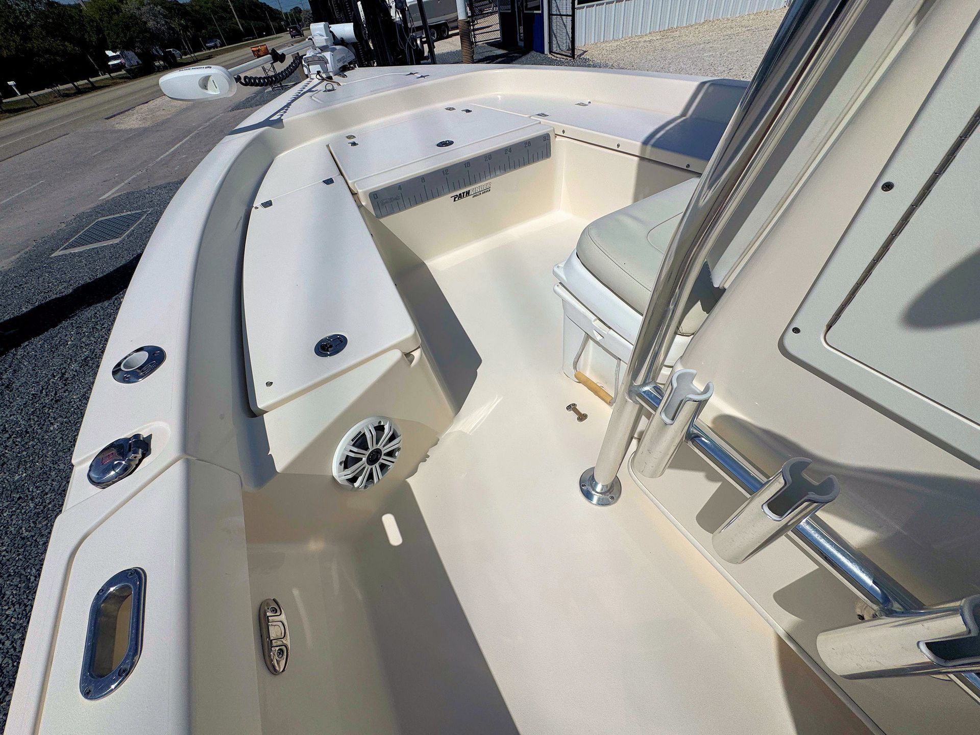 Boat deck with white seating and chrome rails near a dockside view of the water
