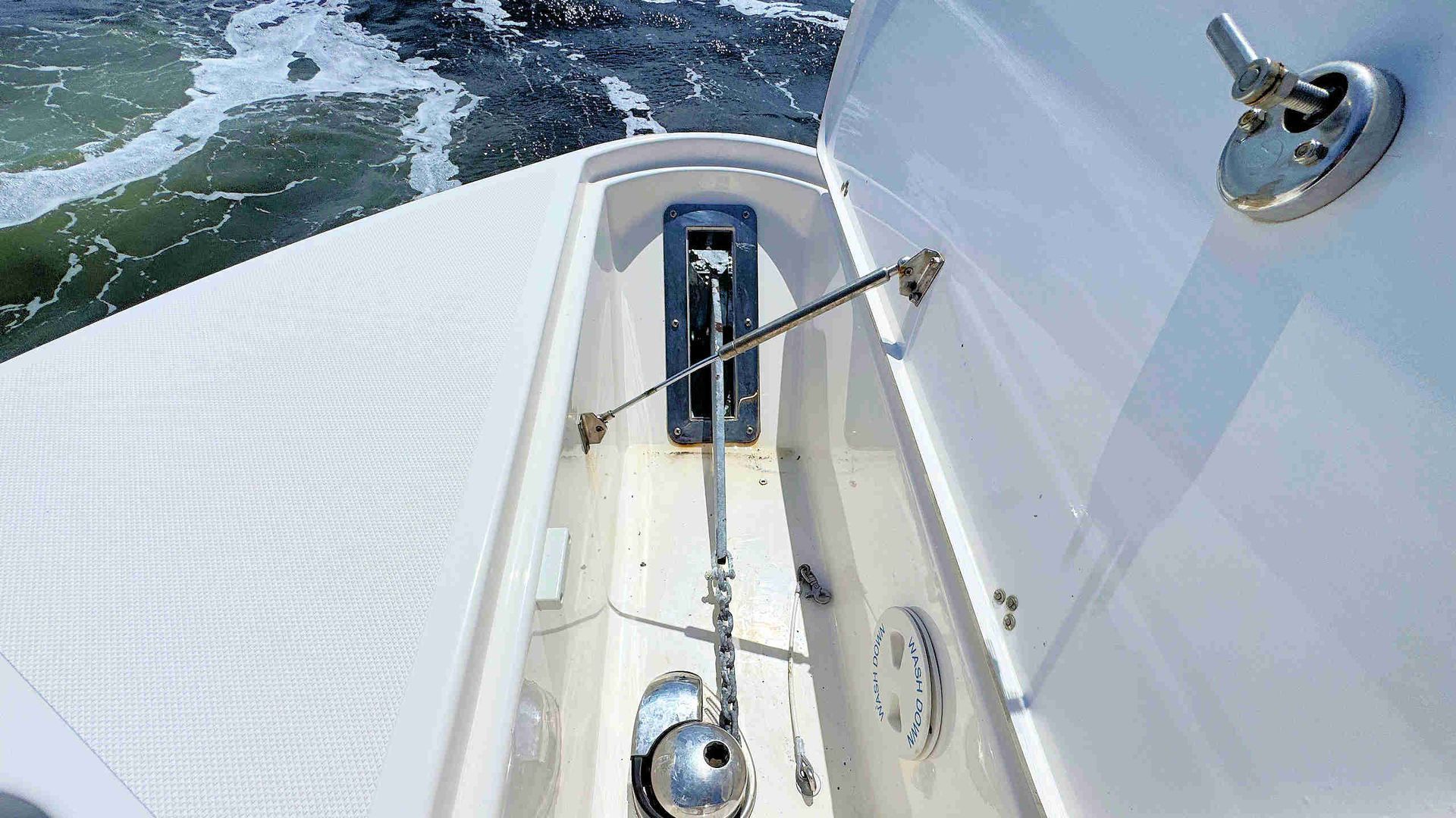 Boat bow with windlass and rigging cutting through choppy blue water