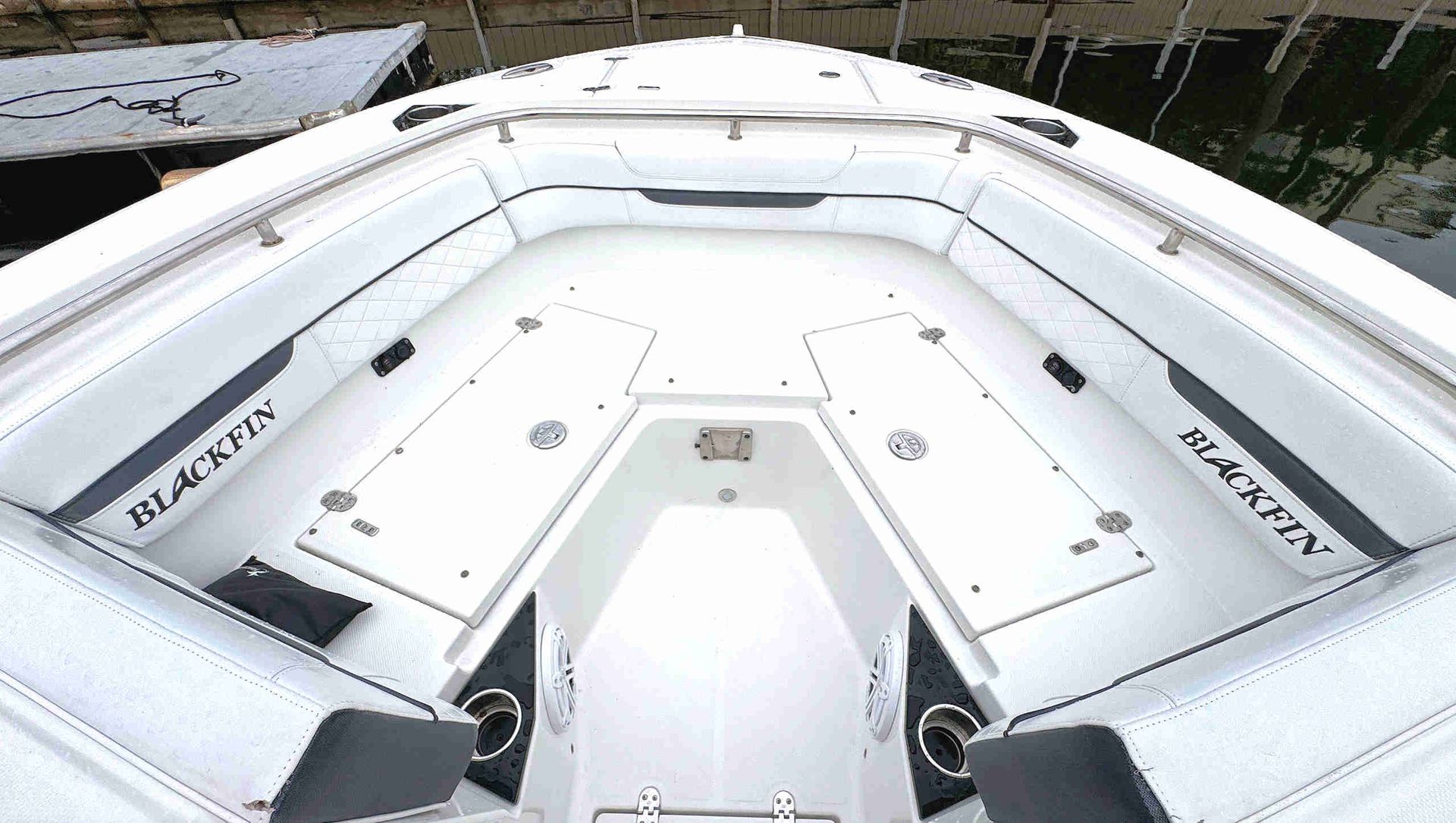 White yacht bow with cushioned deck and black seating, viewed from above on the water