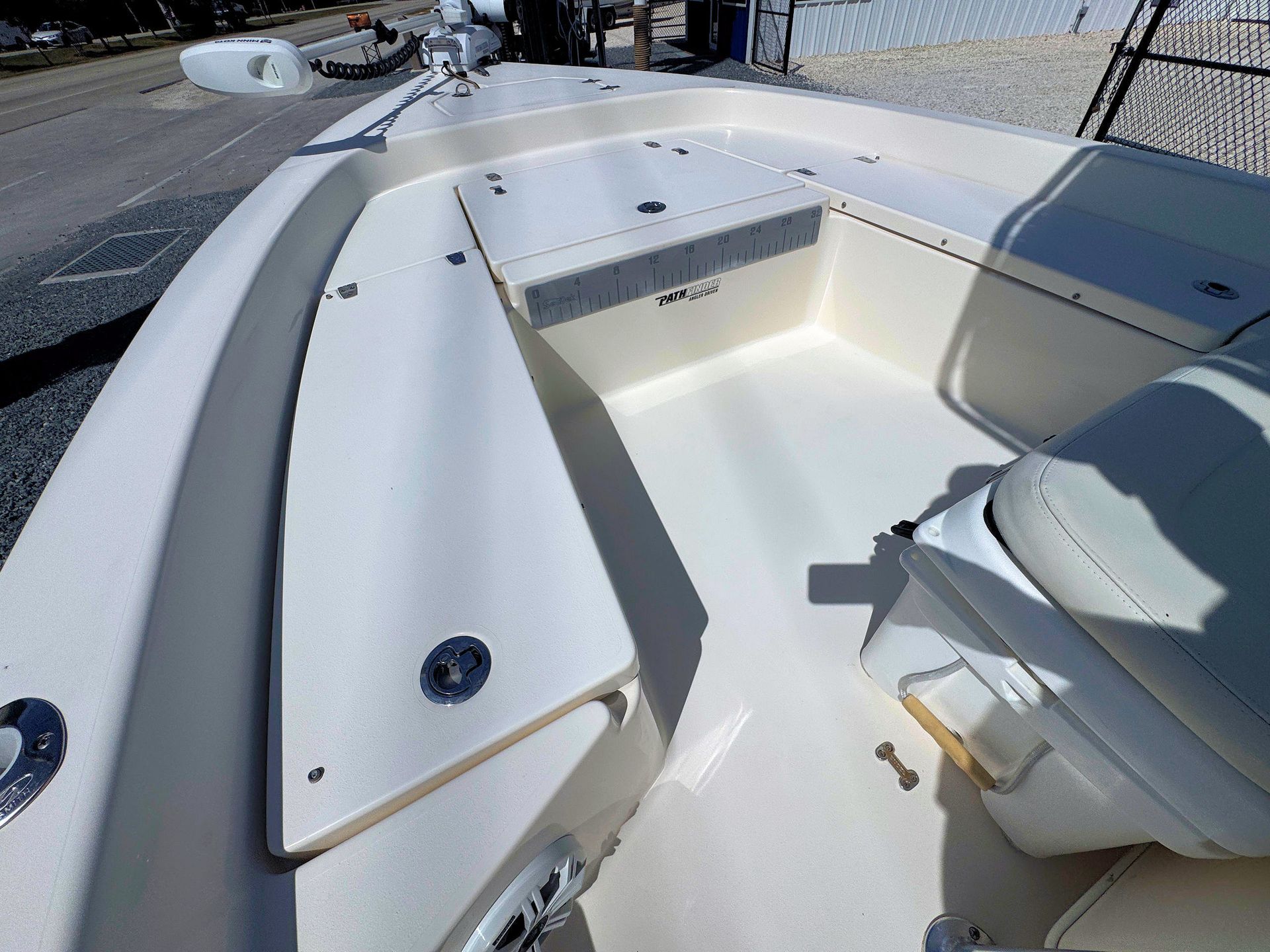 White boat cockpit with cushioned seating and helm, viewed from above in bright sunlight