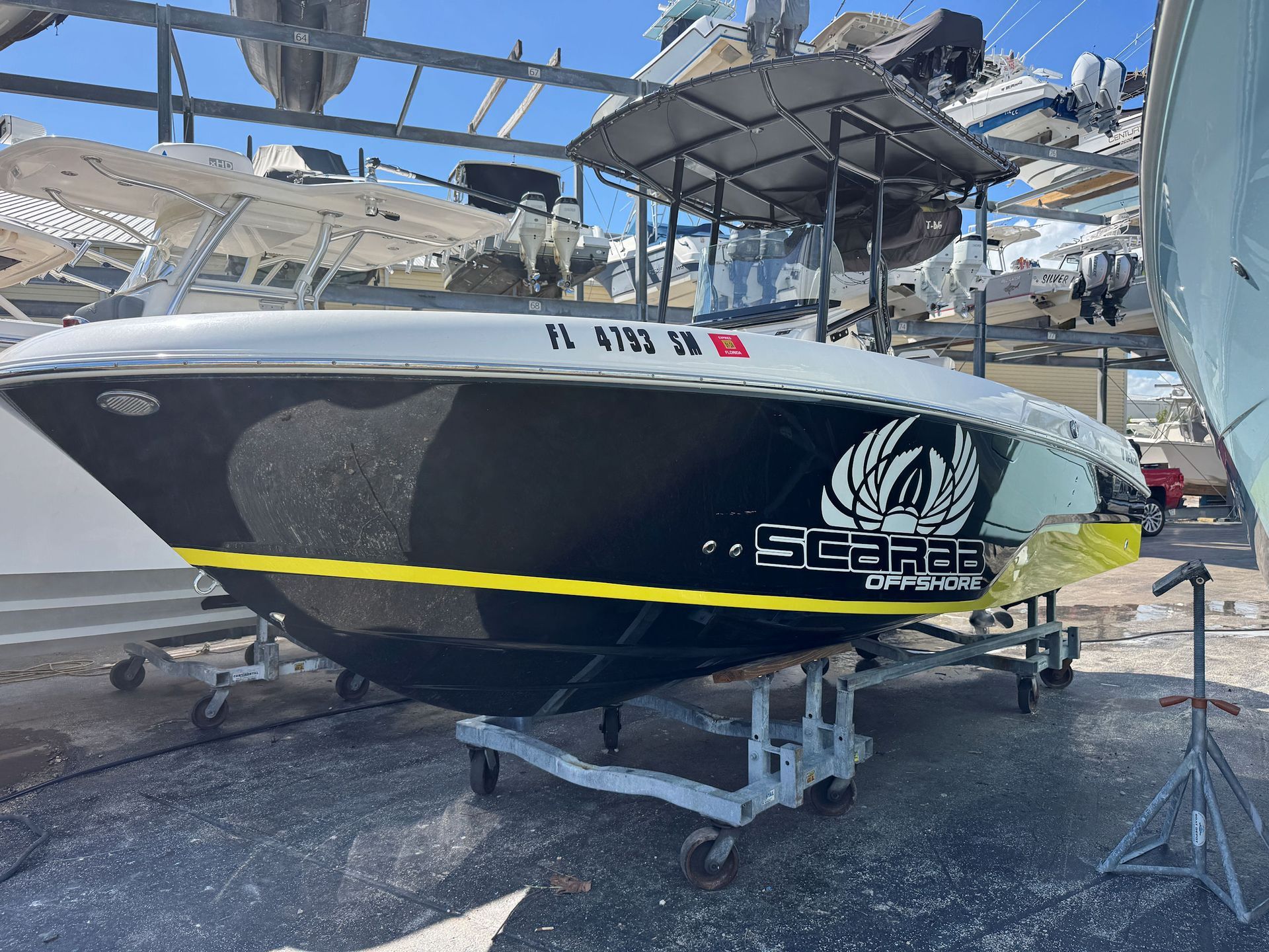 Black-and-yellow center-console boat on a stroller under a storage rack.