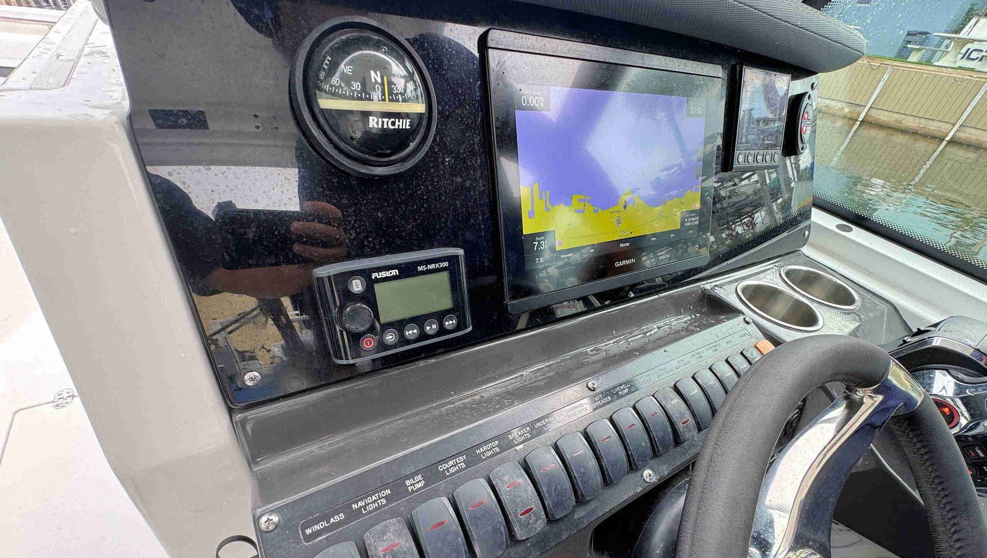 Boat dashboard with navigation display, gauges, and steering wheel in a cockpit interior