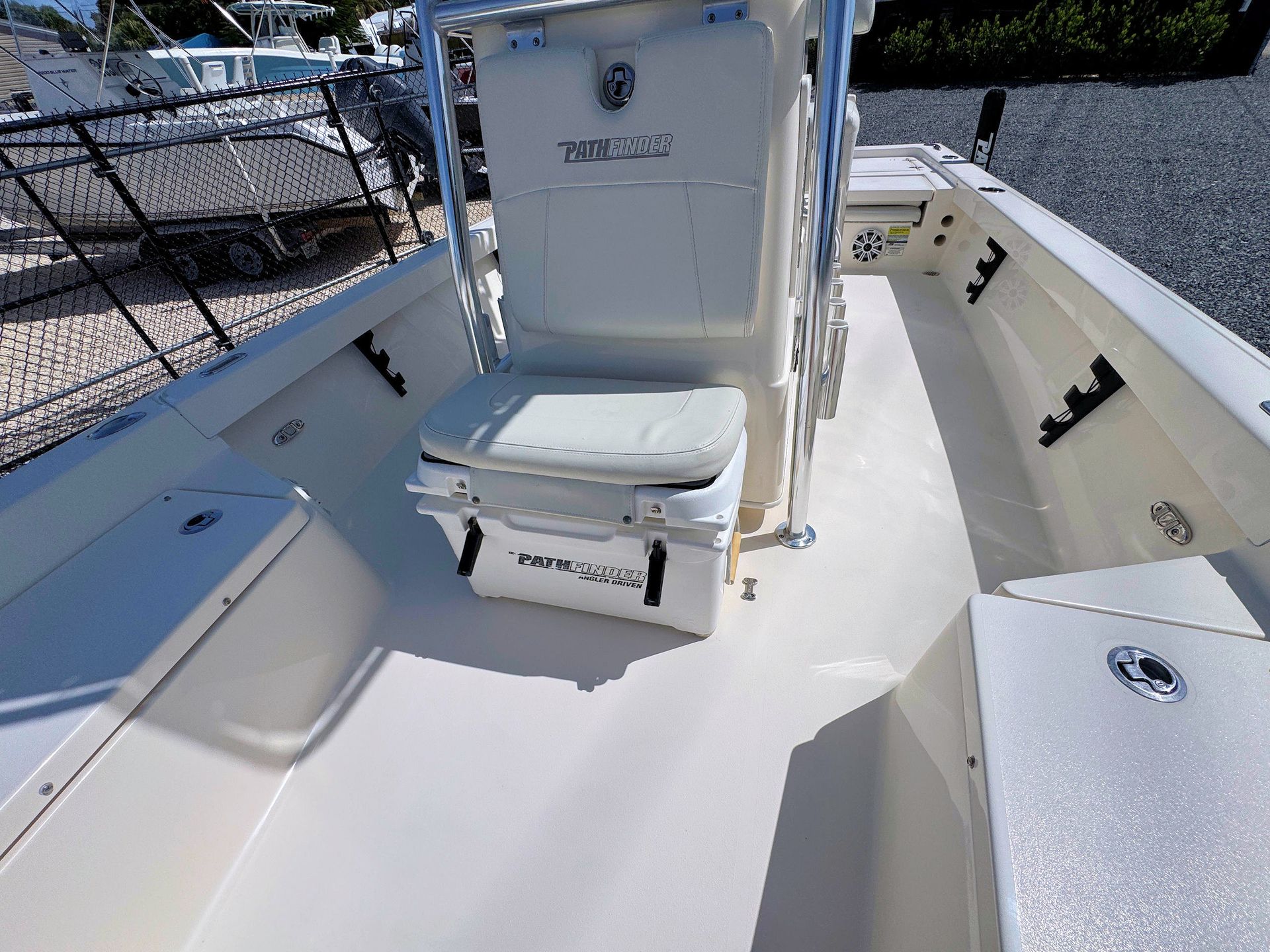 White boat deck with a center seat and storage hatch, viewed from the stern under bright sunlight