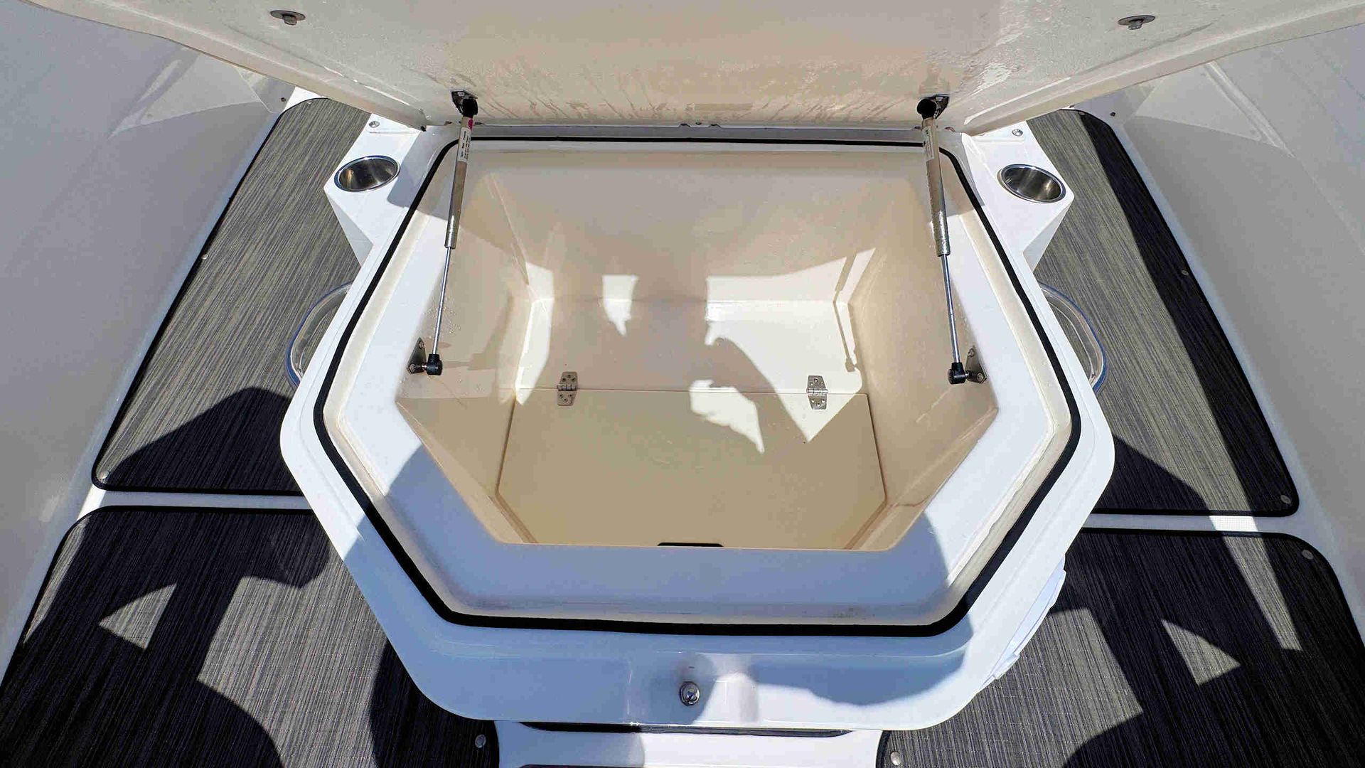 White hatch or cooler lid with beige interior on a boat deck, viewed from above