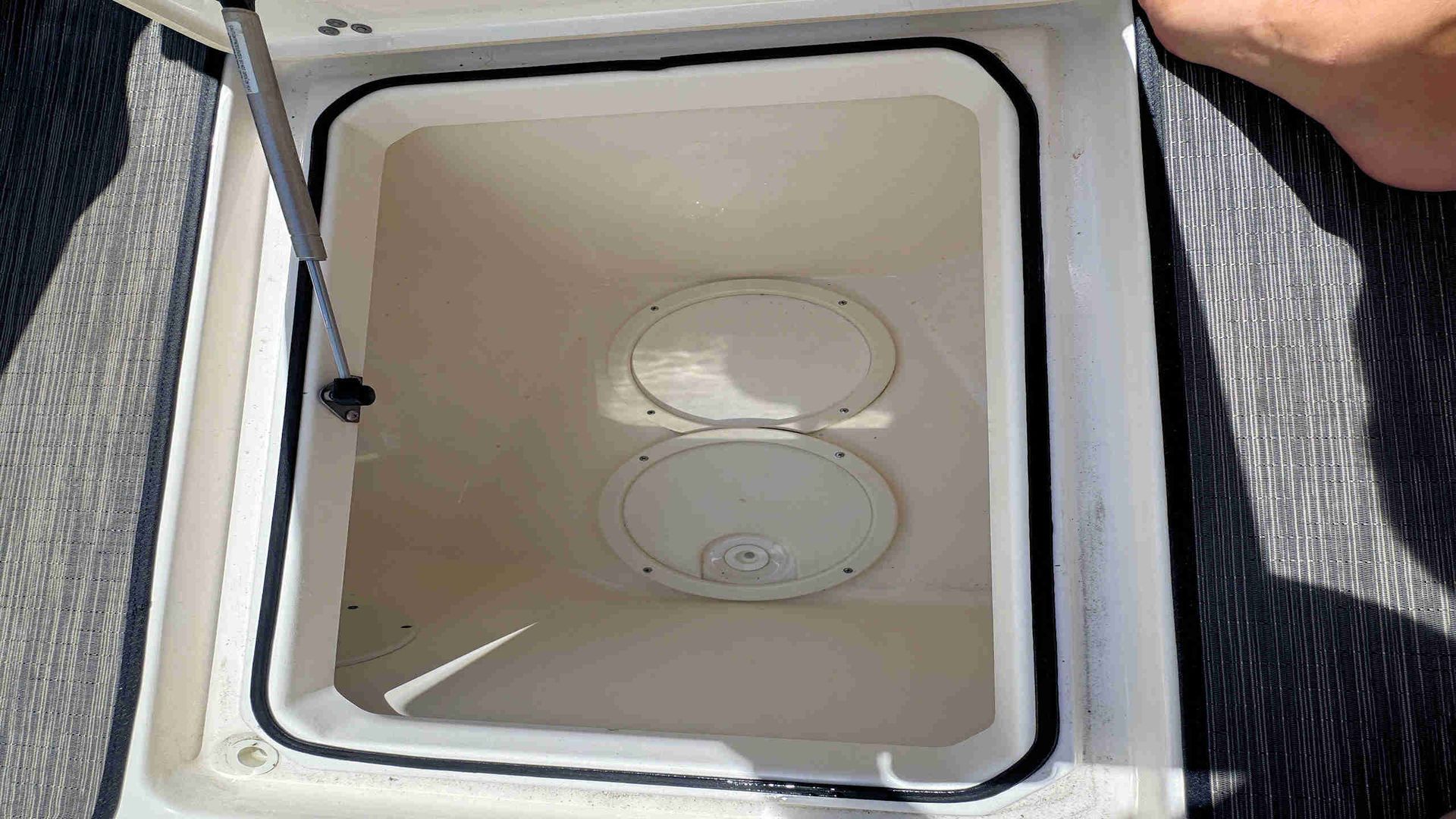 Open insulated cooler box with empty white interior and two circular lids on the bottom
