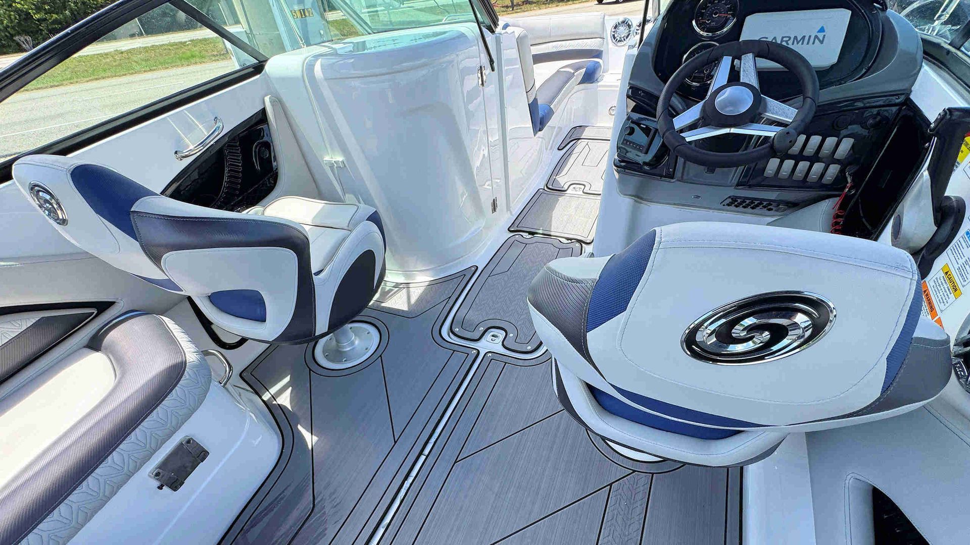 Boat cockpit with white and blue seating, steering wheel, and helm controls on a sunny day