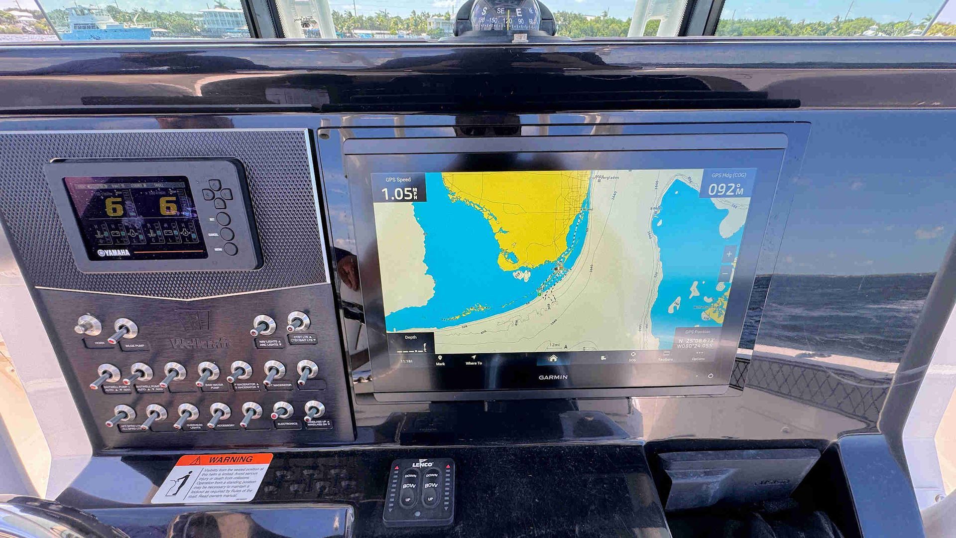 Boat dashboard with GPS navigation screen, radio controls, and reflections on the windshield.