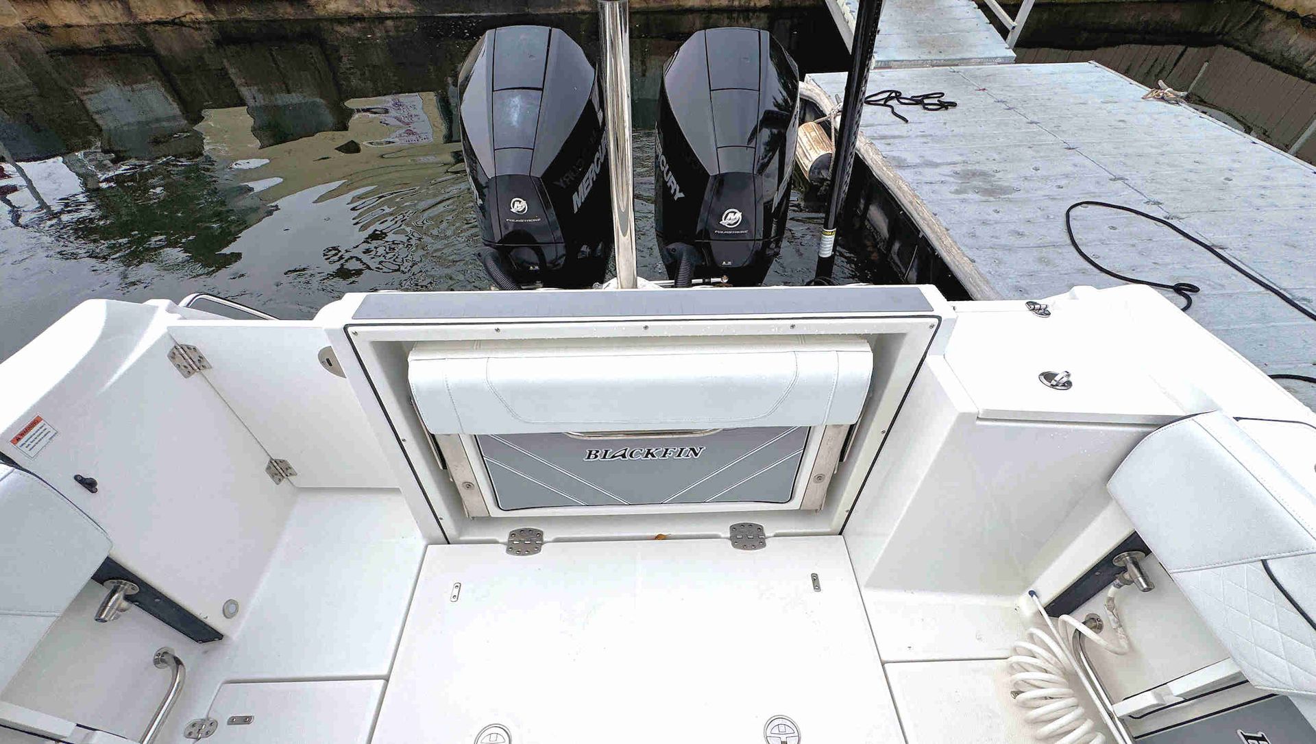 Boat deck with a rear transom door and two outboard motors at the stern, viewed from above