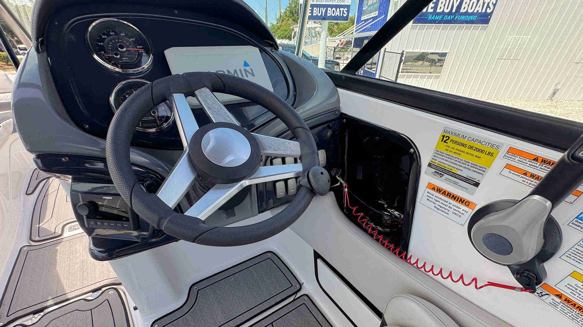 Boat helm with steering wheel, throttle, and dashboard inside a white cockpit.