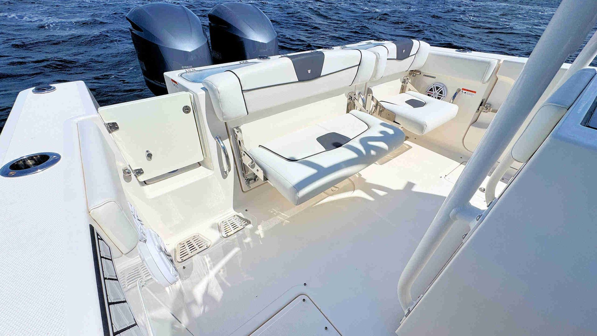 Boat deck with white seating and two outboard motors on the water