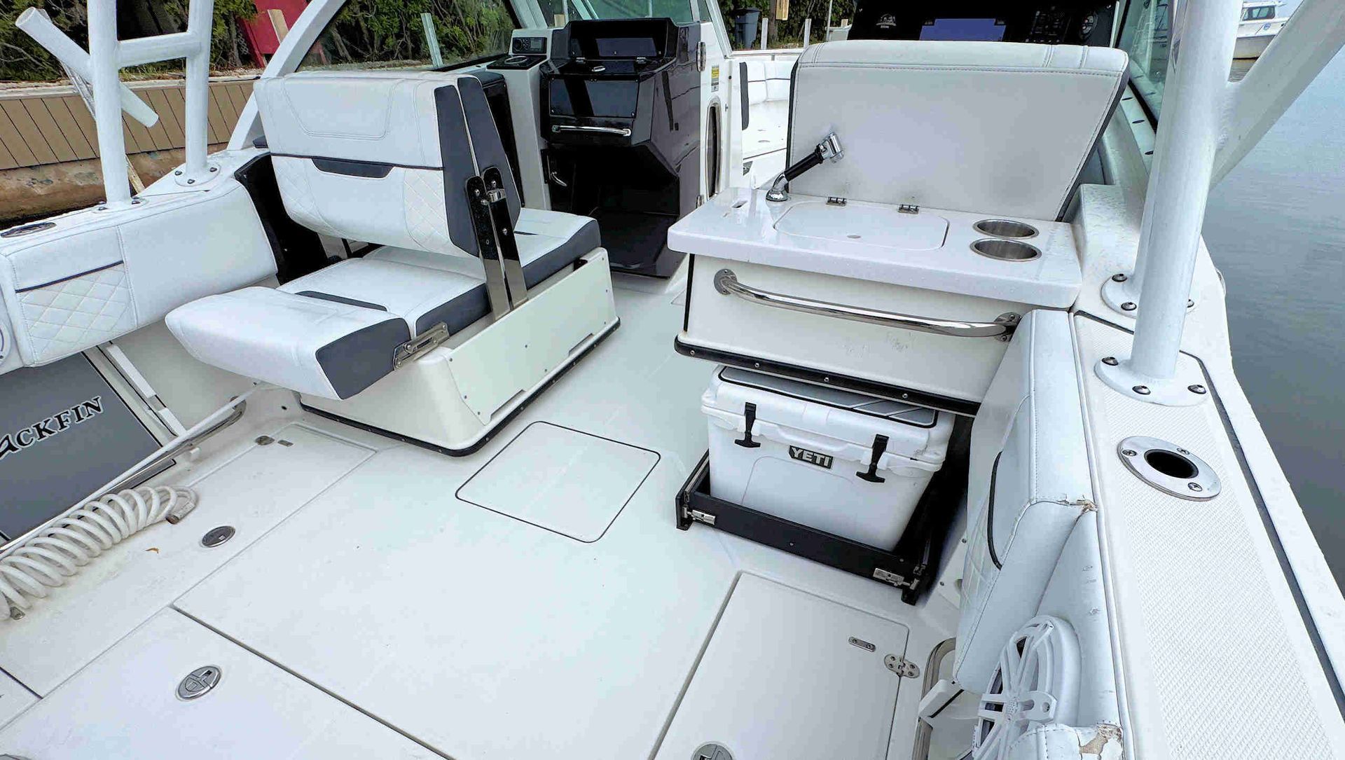 White fishing boat deck with two padded seats and storage hatches in bright daylight