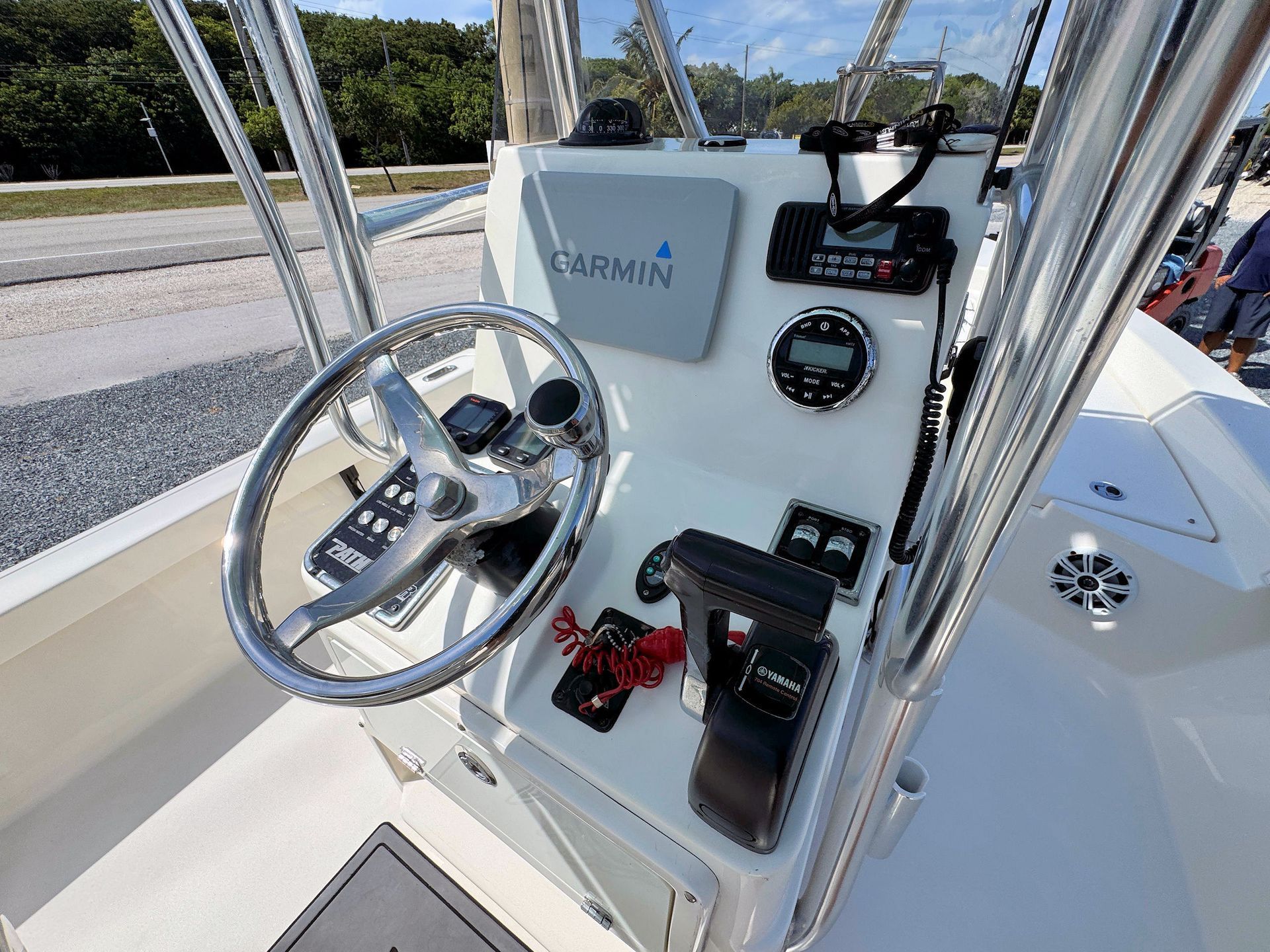 Boat helm with stainless-steel steering wheel, gauges, and controls in a bright cockpit area