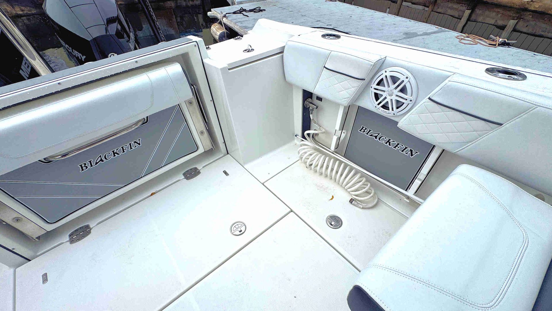 White boat cabin interior with cushioned seating, small table, and windows overlooking water