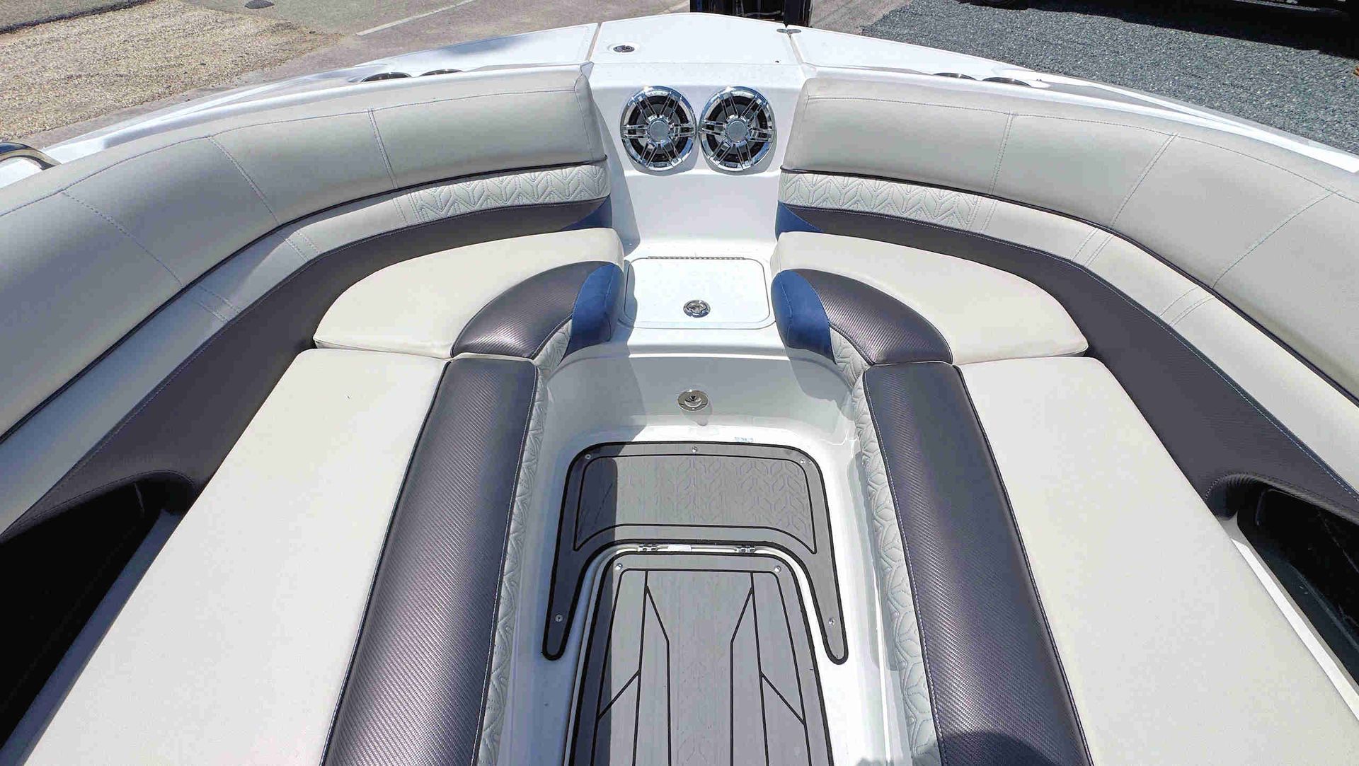 Interior of a speedboat with white and gray cushioned seating and a central control panel