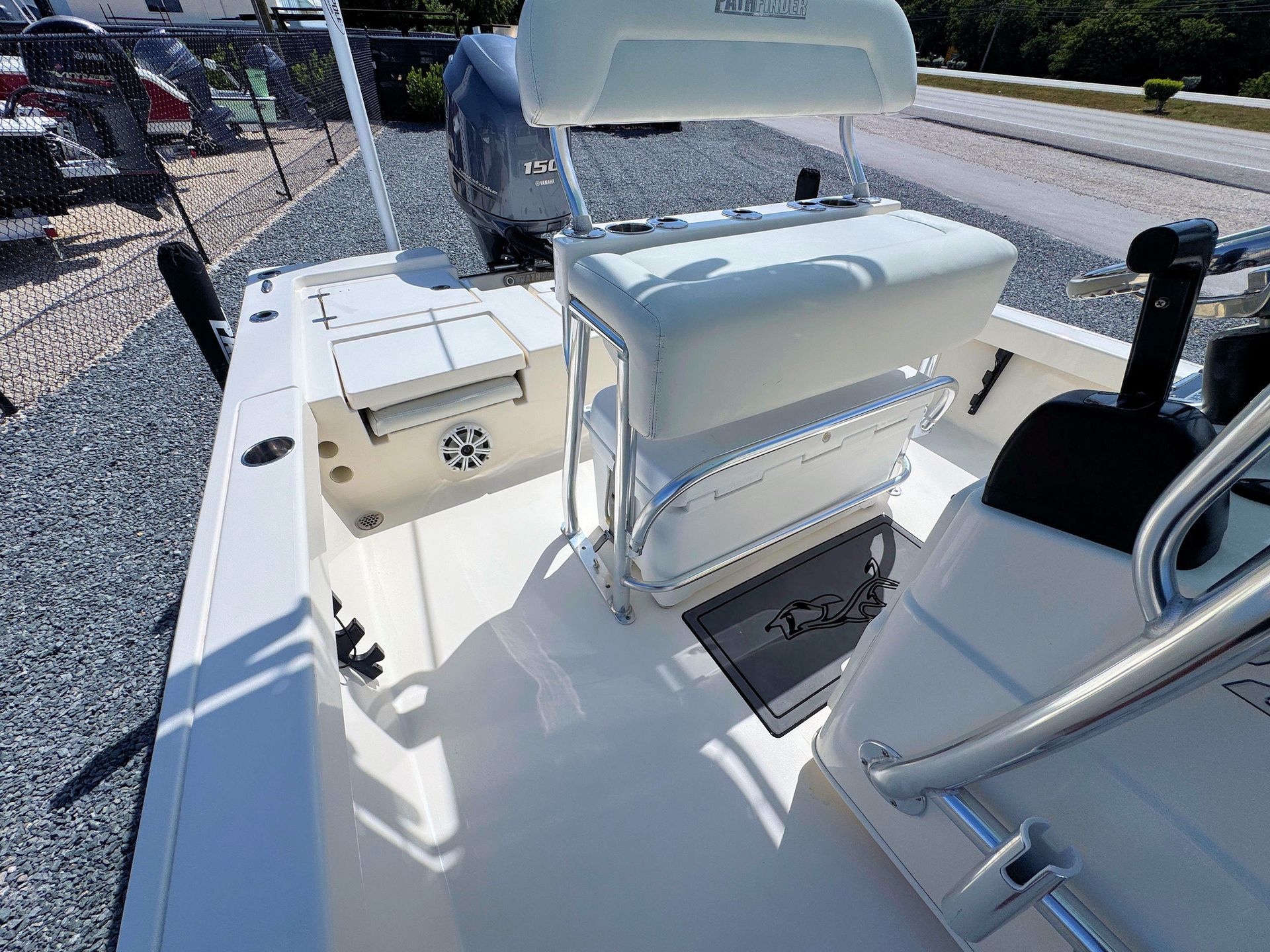 White boat cockpit with cushioned seats and a fold-down bench on a sunny docked vessel