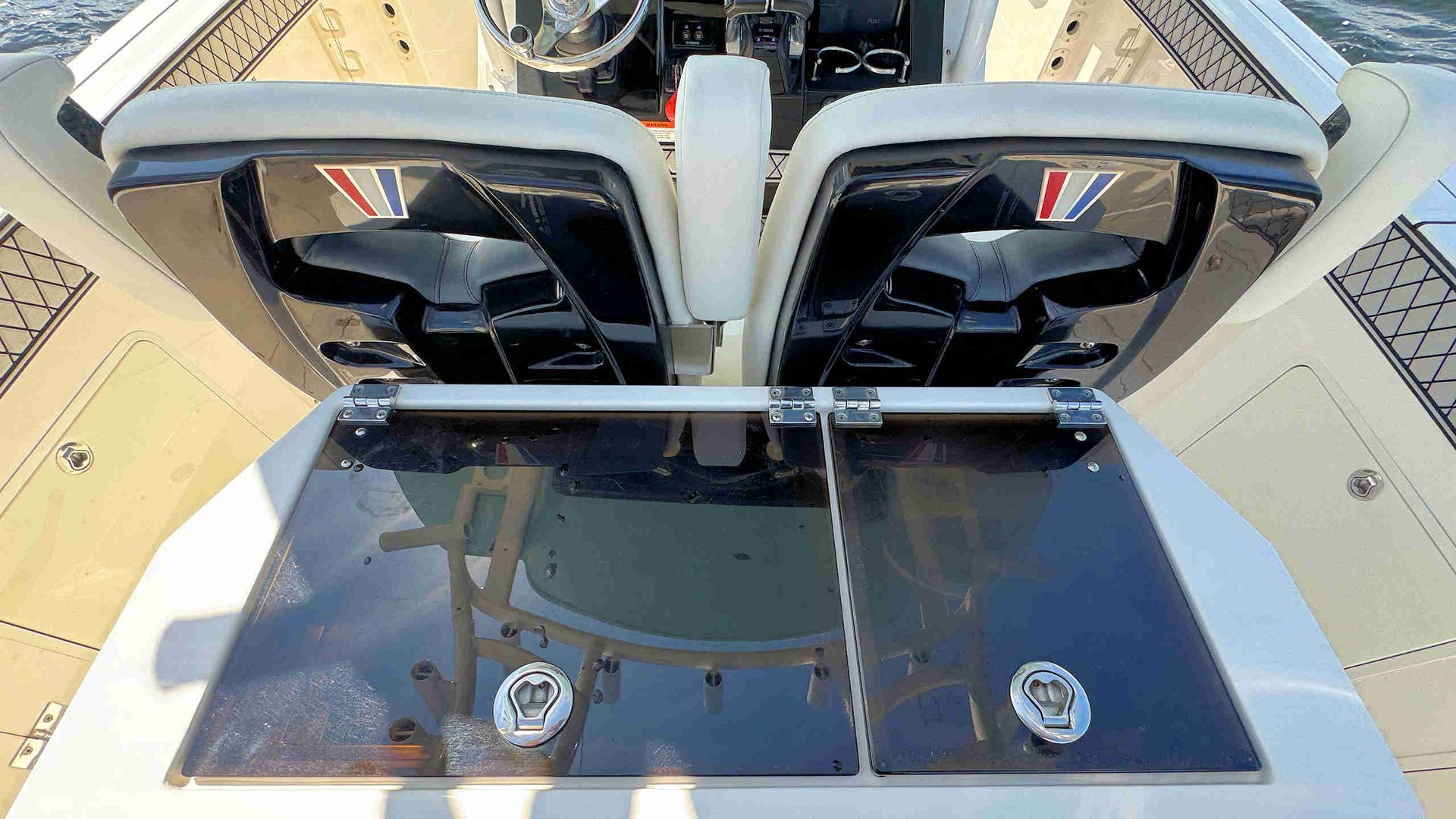 Aerial view of two black seats and a glass tabletop on a boat deck