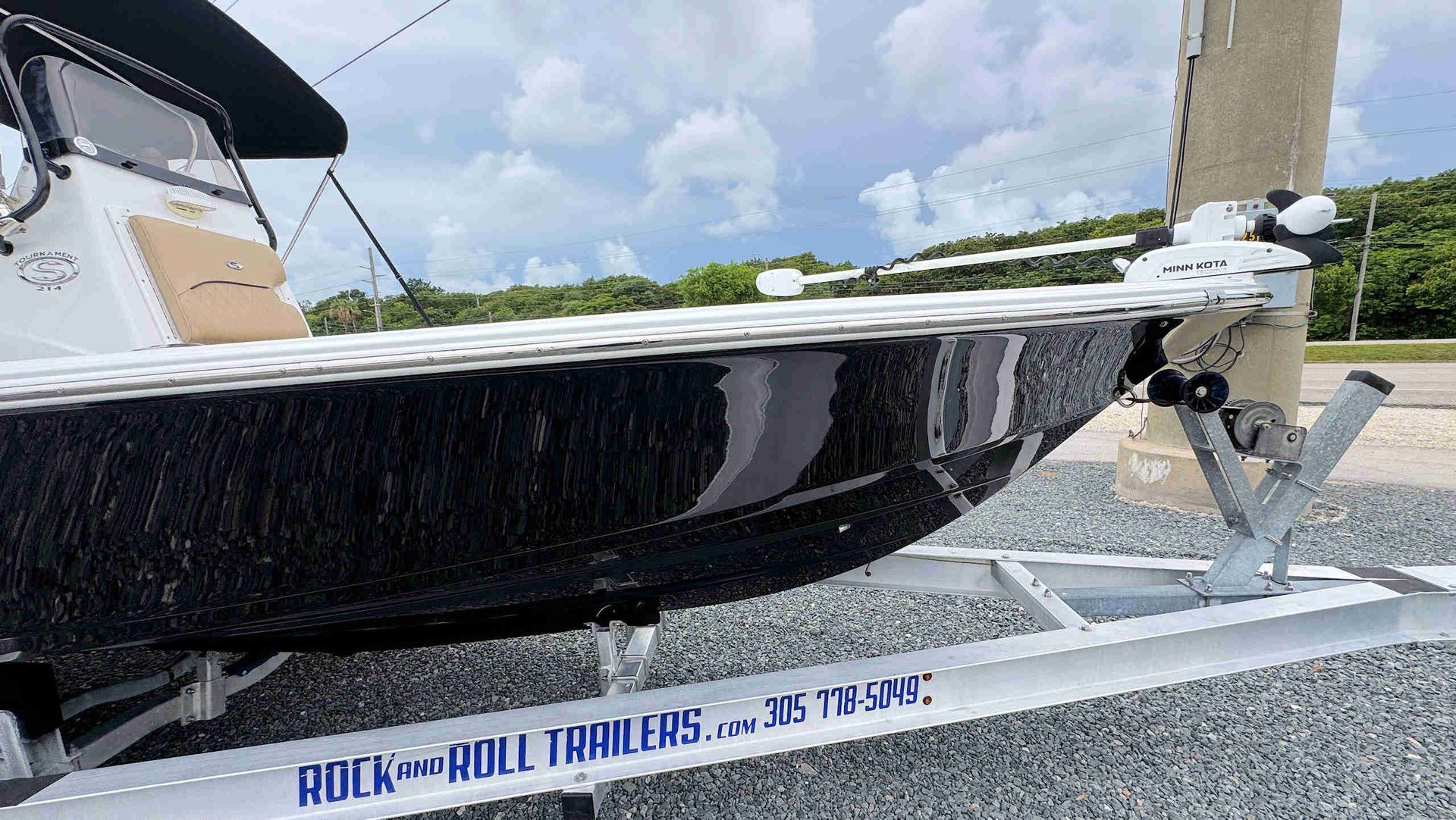 Black center console fishing boat on a trailer under a partly cloudy sky
