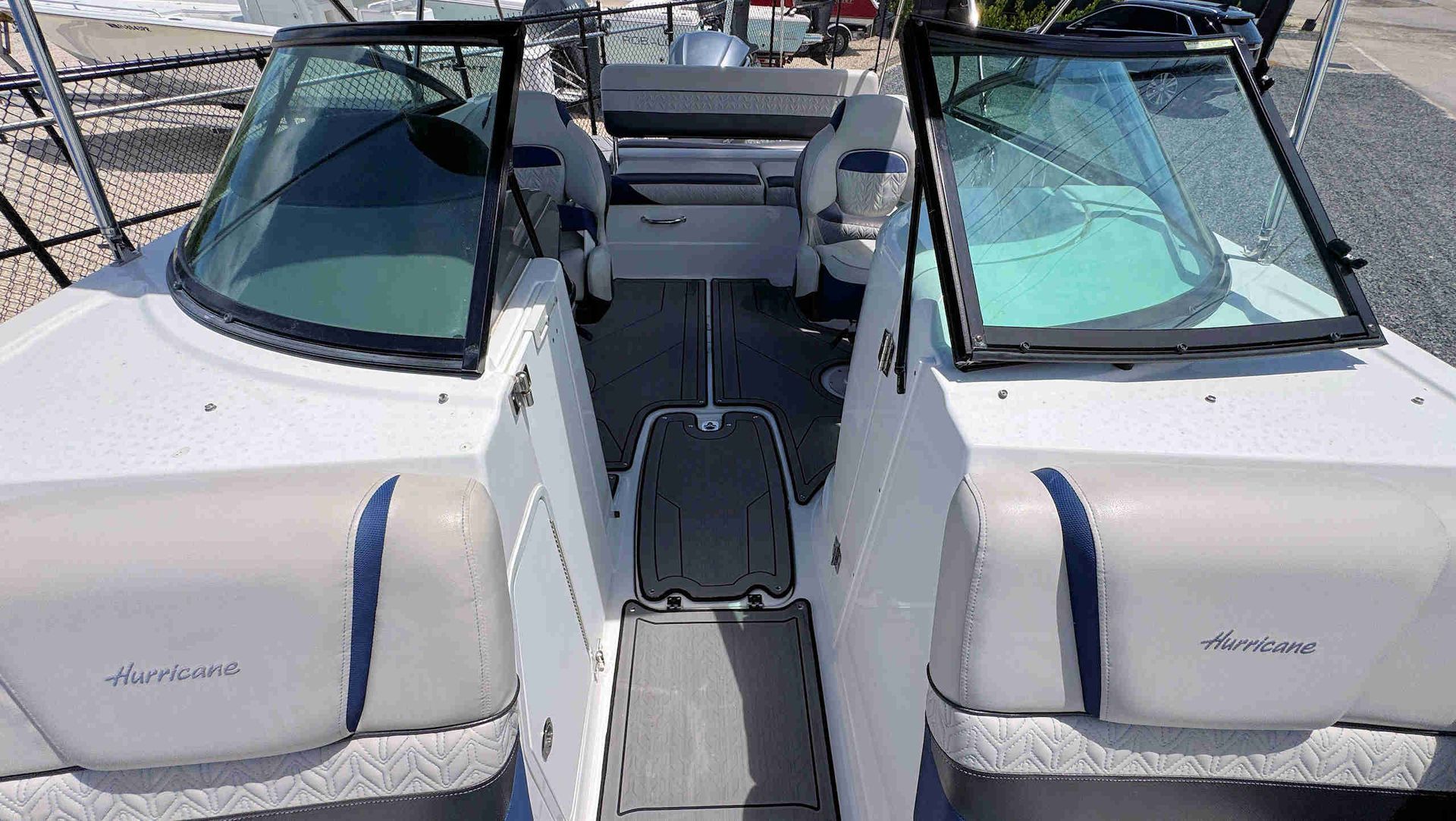 View of a boat cockpit with two open white hatches and a gray center walkway under sunlight
