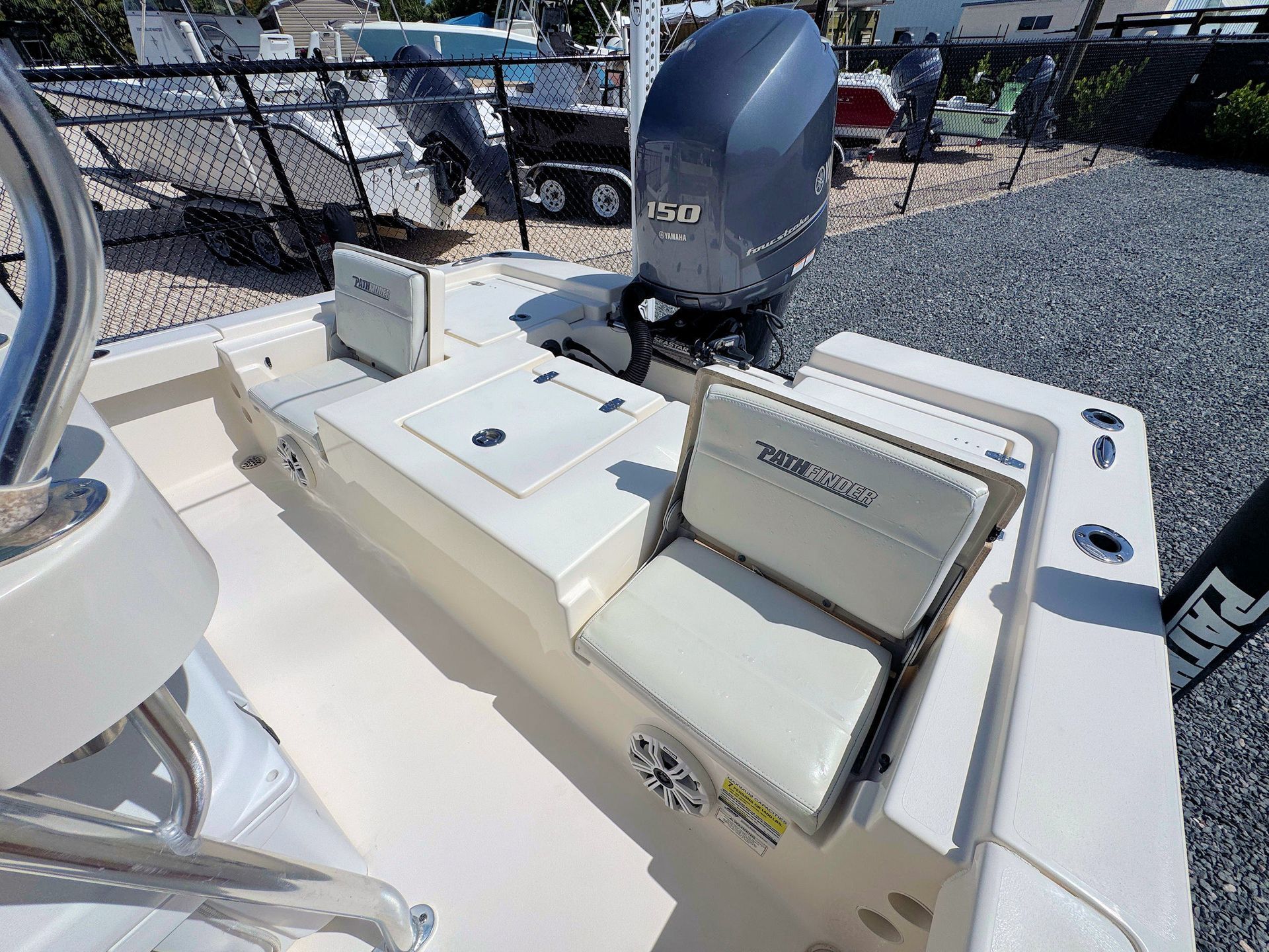 Boat stern with cushioned seating, and gray outboard motor on a dockside deck