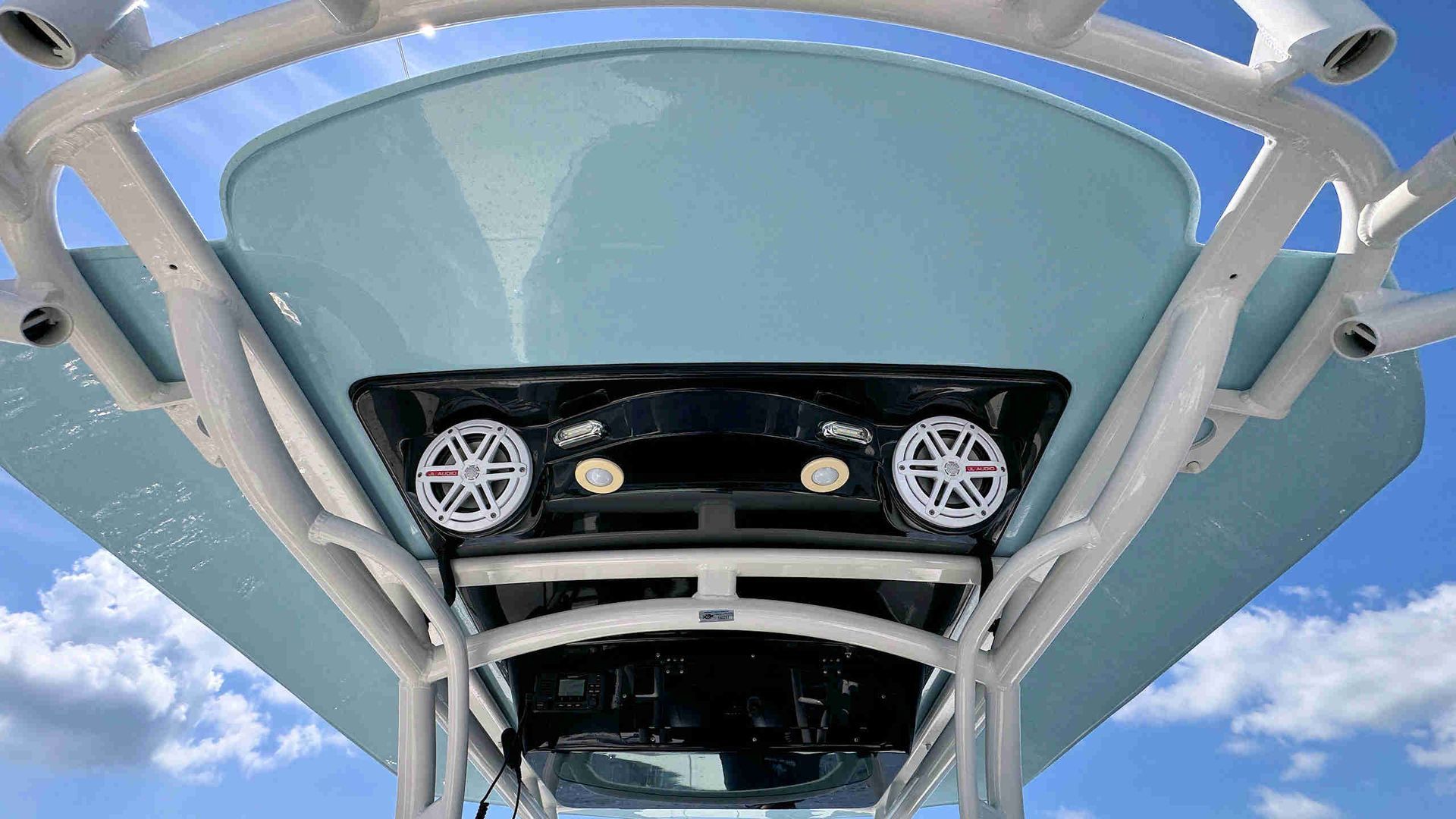 Underside of a fiberglass t-top with speakers and a skylight against blue sky
