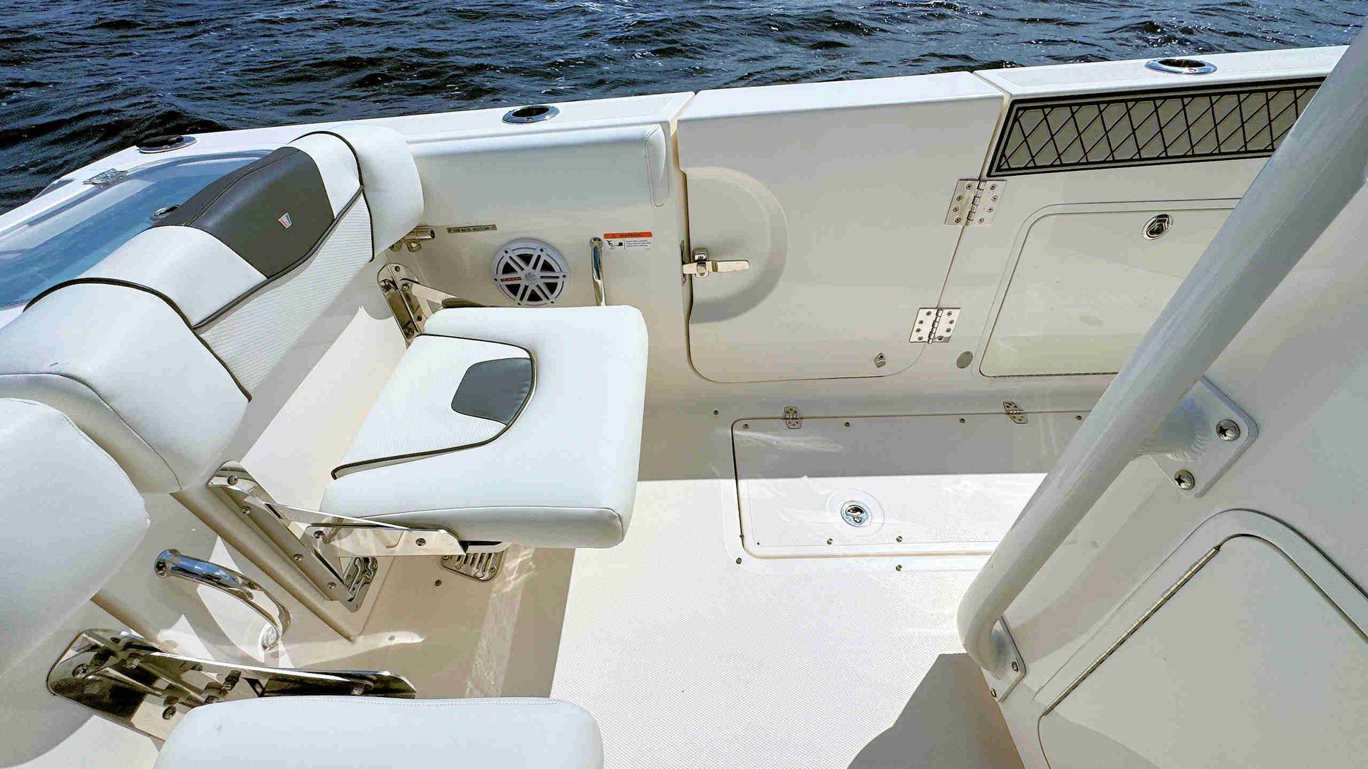 Boat cockpit with white seats and deck overlooking blue water