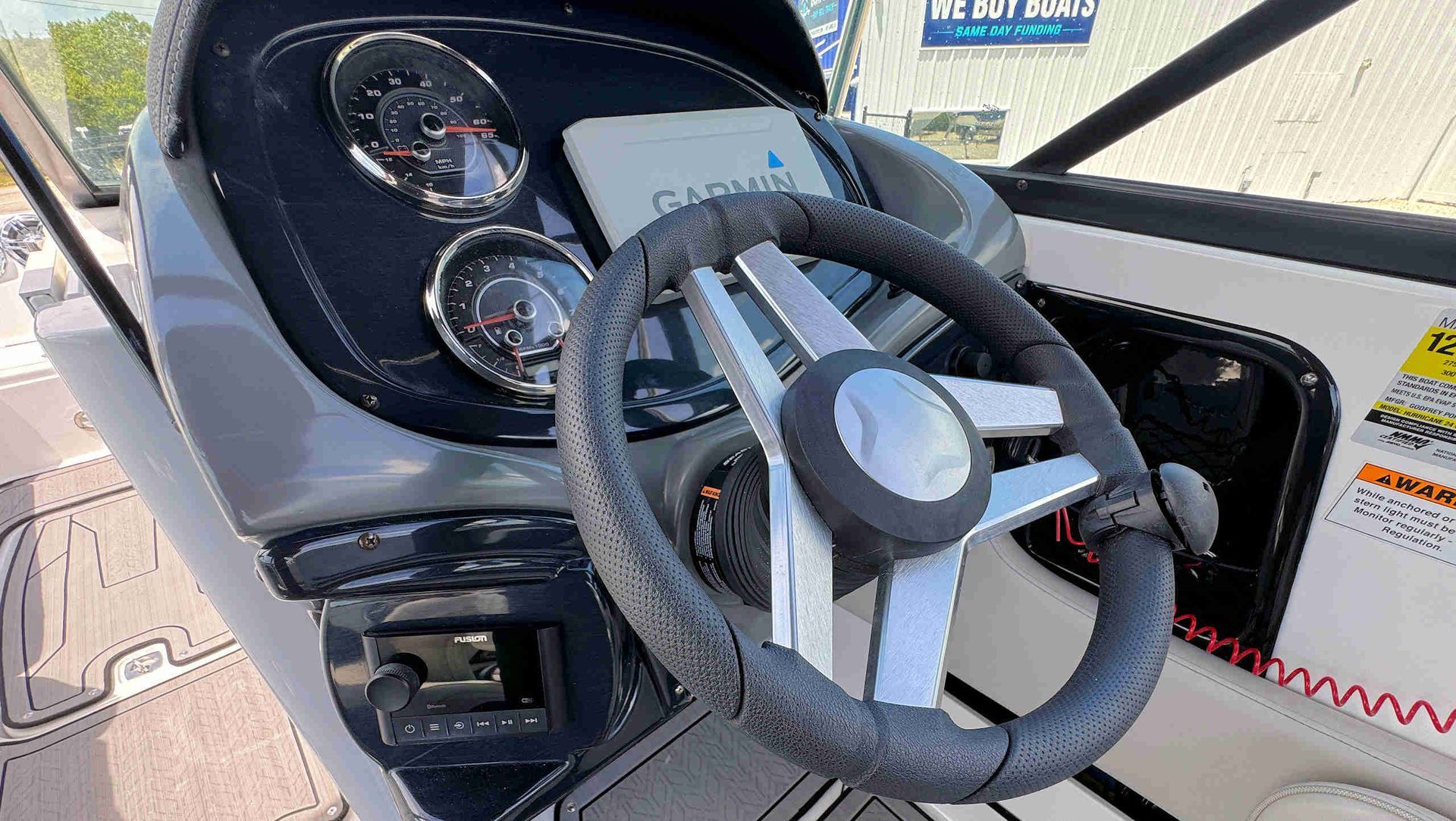 Boat steering wheel and gauges on a sunlit helm console