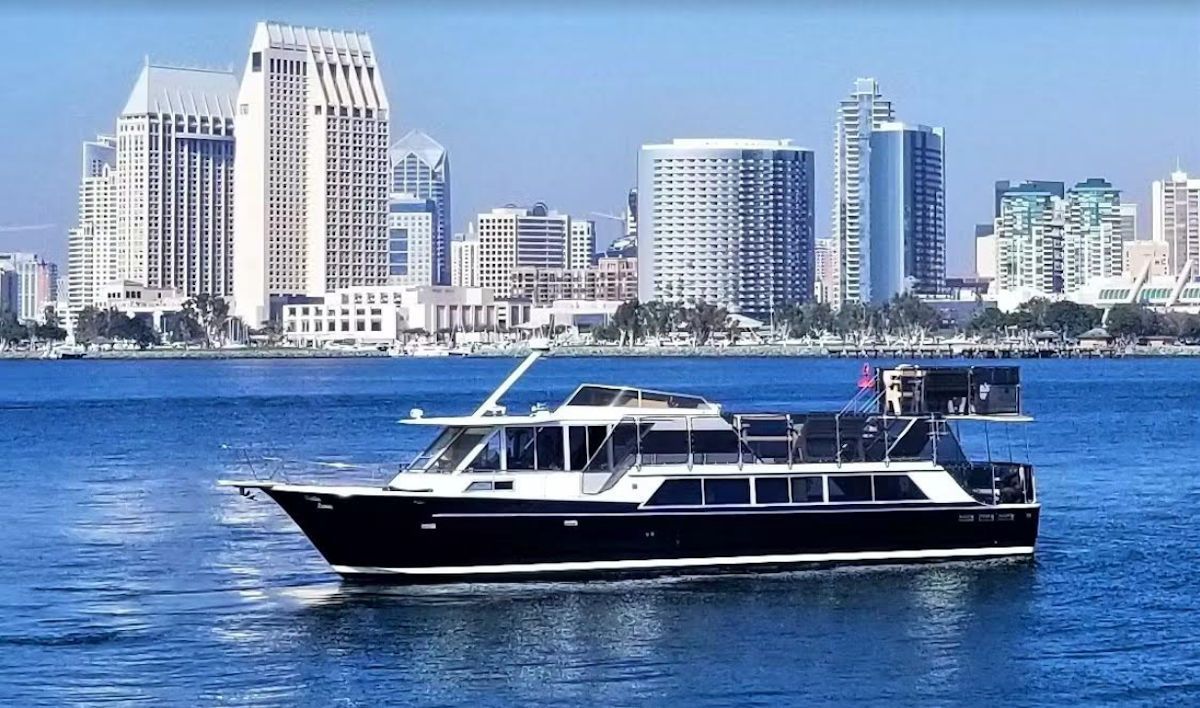 A boat is floating on a body of water in front of a city skyline.