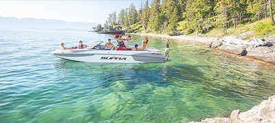 People on a boat near a rocky shore with clear, turquoise water and a treed backdrop.