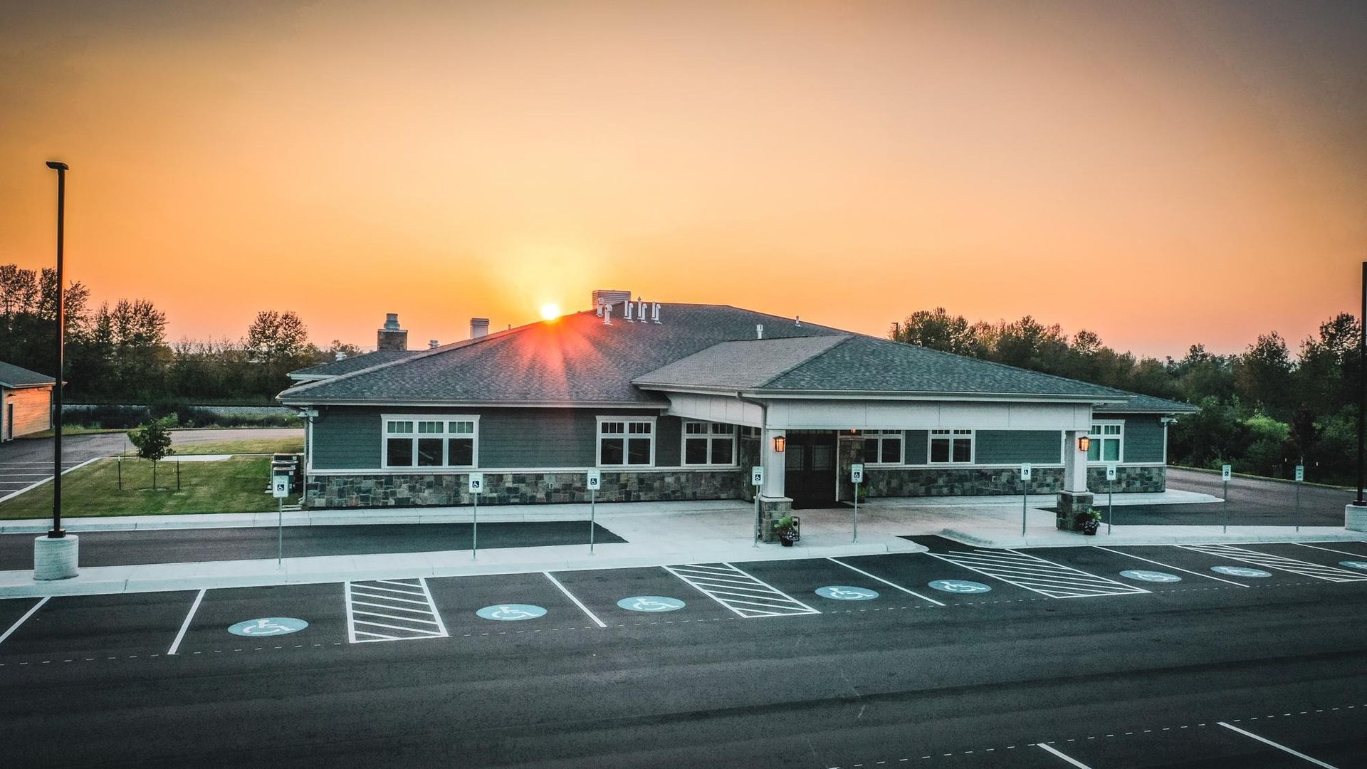 Building exterior with parking and sunset in the background. Accessible parking spaces.