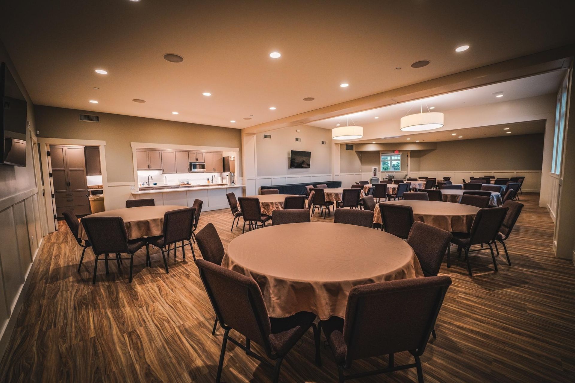 Round tables with chairs in a beige-toned room, likely for a gathering or event.