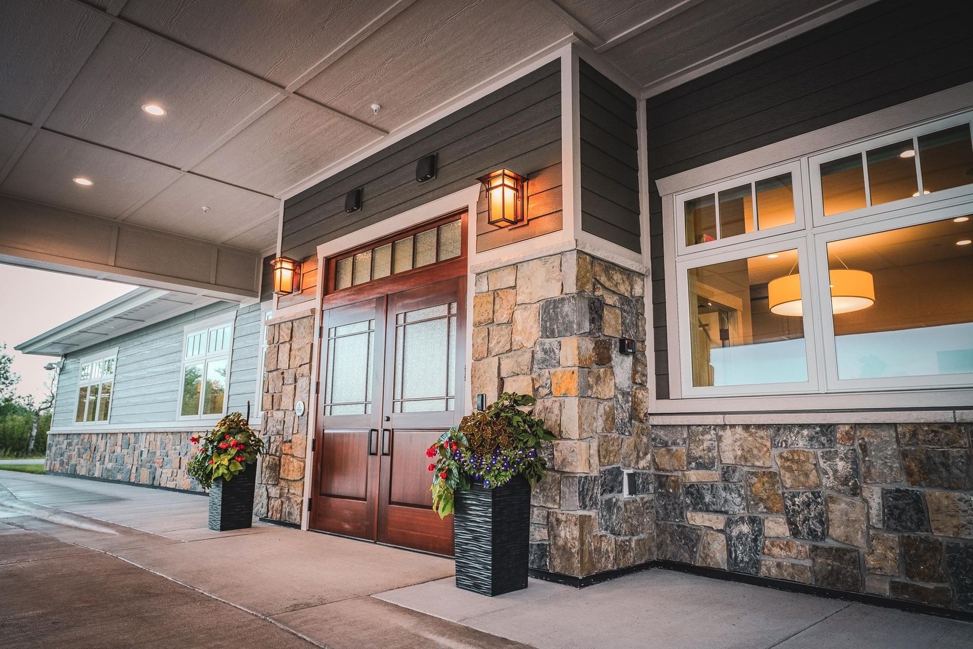 Exterior entrance with stone and wood accents, double doors, and planters.