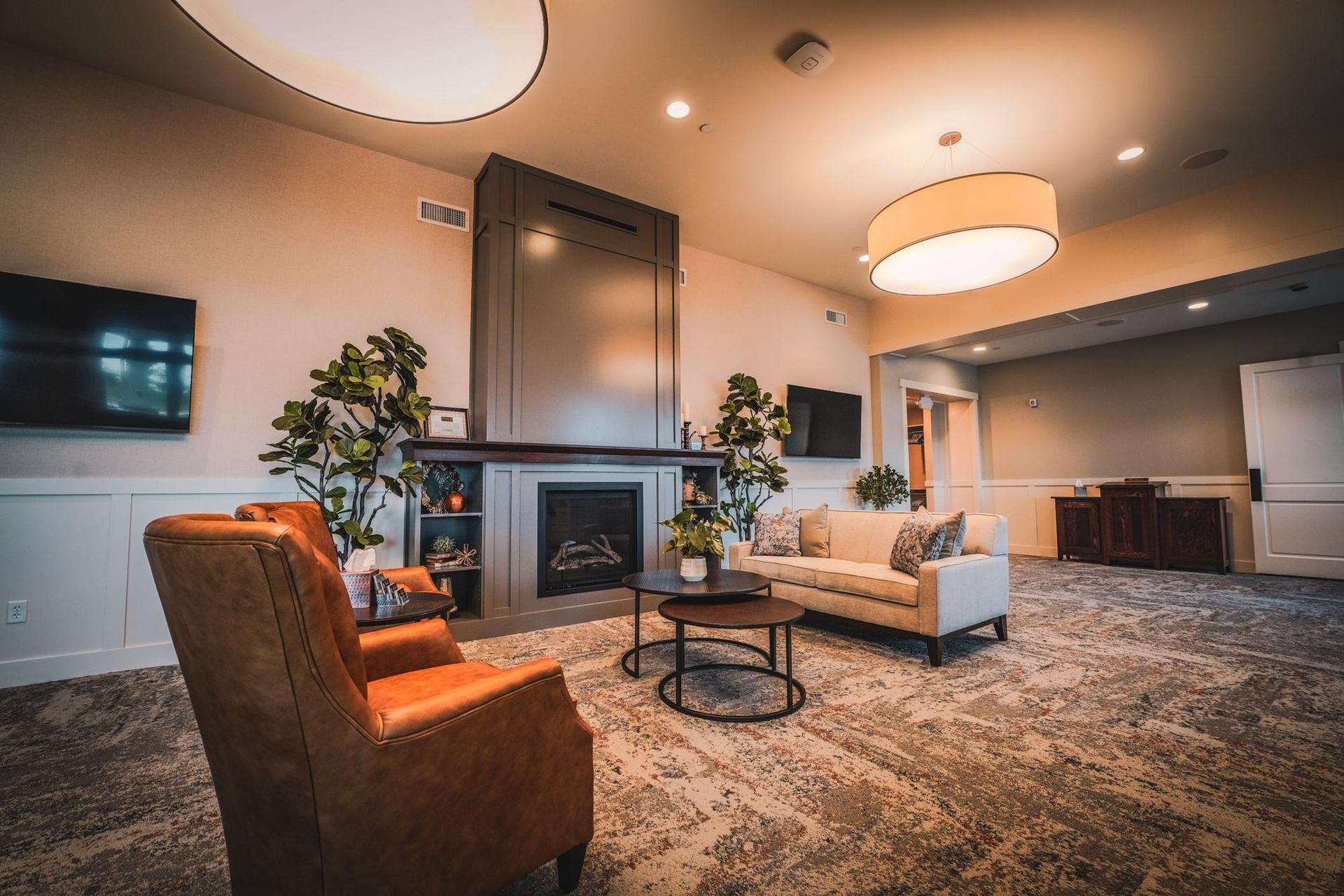 Cozy living room with fireplace, armchairs, sofa, and round coffee tables.