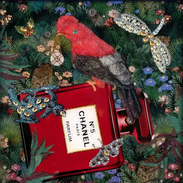Red Chanel perfume bottle with jeweled bird on a dark floral background