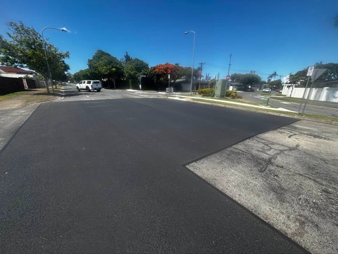 Quiet suburban street with a new black asphalt road under a clear blue sky
