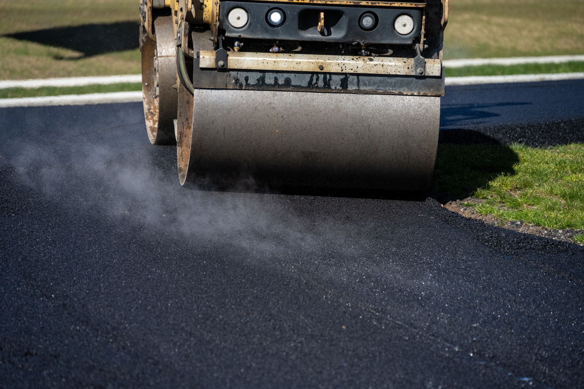 A close-up of a steamroller turning into a freshly paved driveway to compact the hot asphalt. A close-up of a steamroller turning into a freshly paved driveway to compact the hot asphalt.