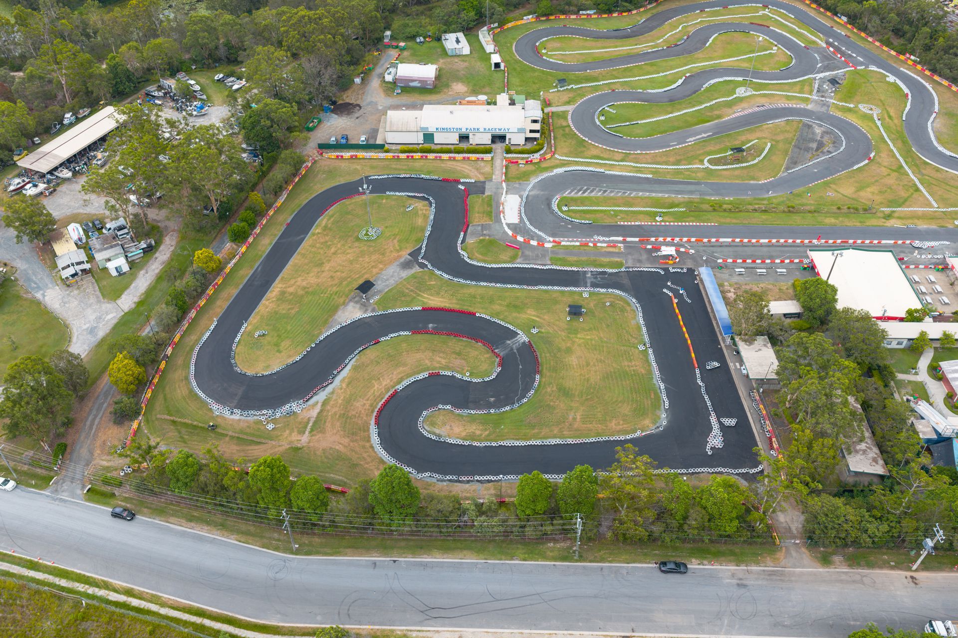Aerial view of an outdoor go-kart track with winding asphalt lanes and surrounding trees.