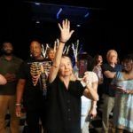 woman holding up hand in crowd