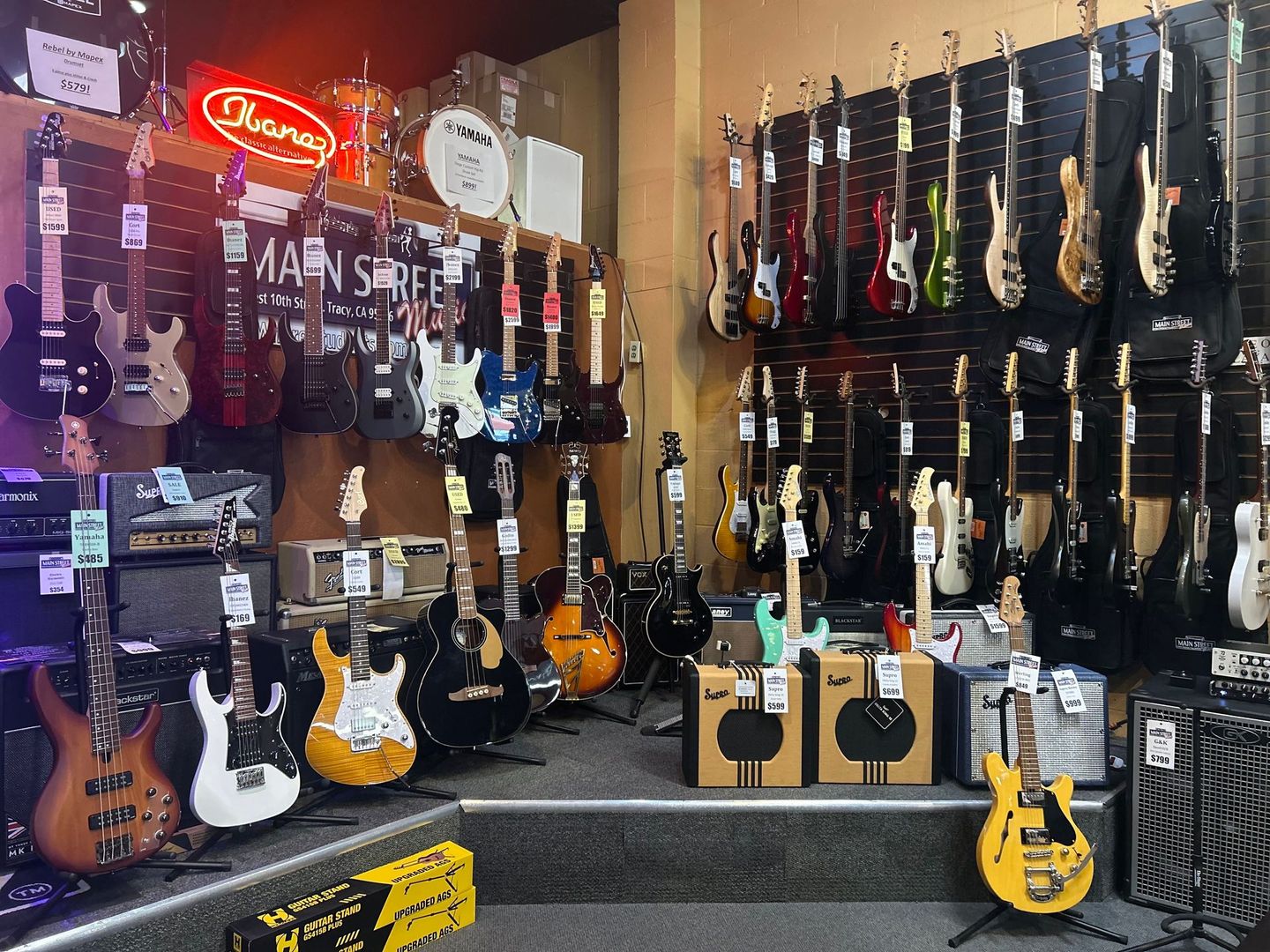 A bunch of guitars are hanging on a wall in a store.