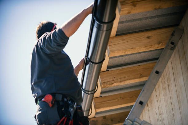 Low angle view of a contractor installing a round metal gutter