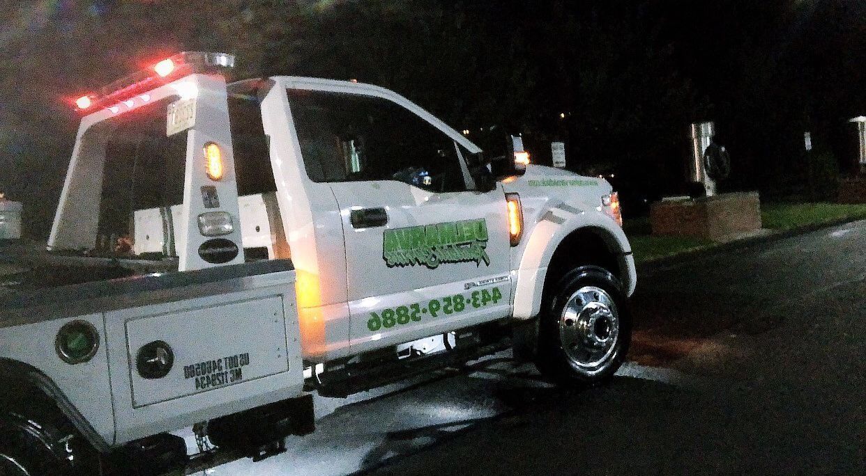Tow truck with flashing lights parked on a wet road at night